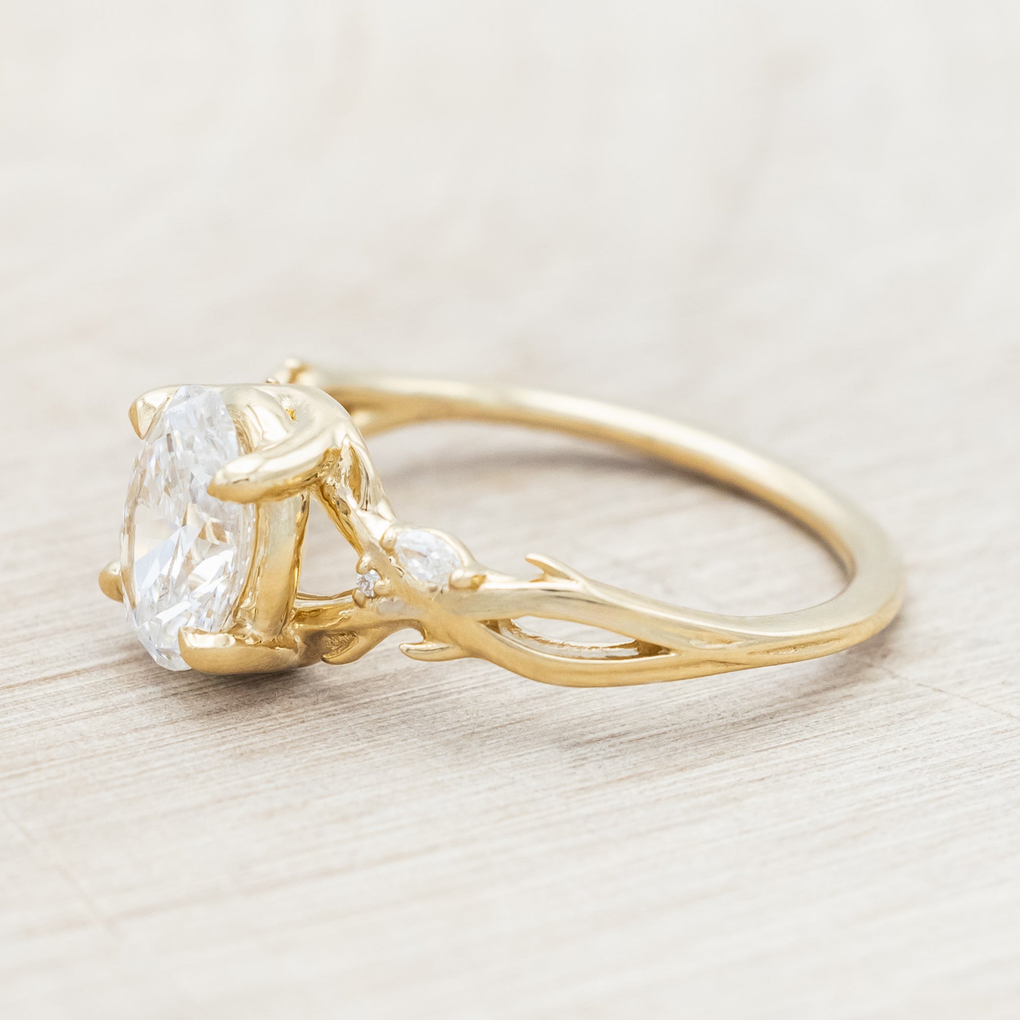 14K gold engagement ring with oval lab-grown diamond and accents against beige background
