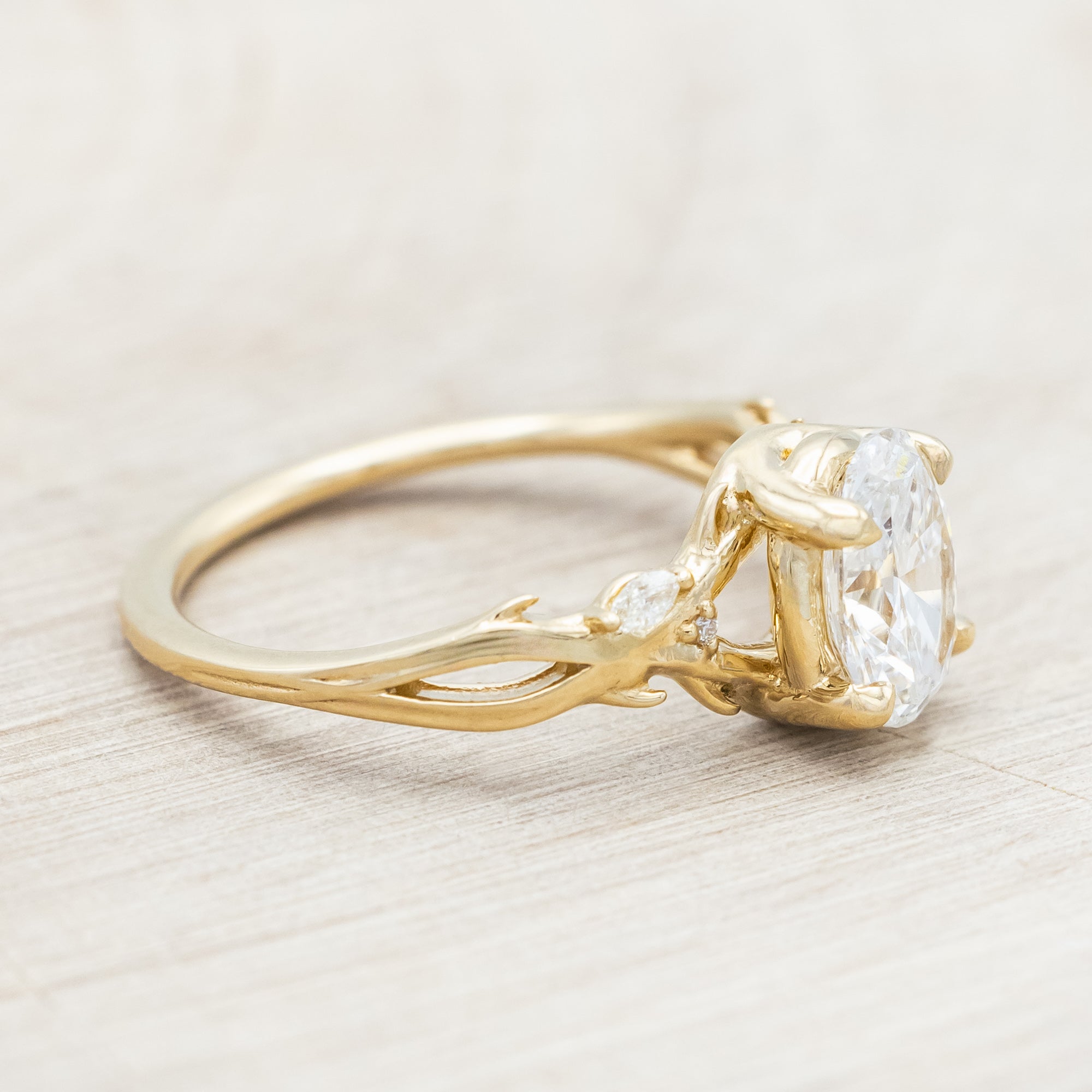 14K gold engagement ring with oval lab-grown diamond and accents against beige background