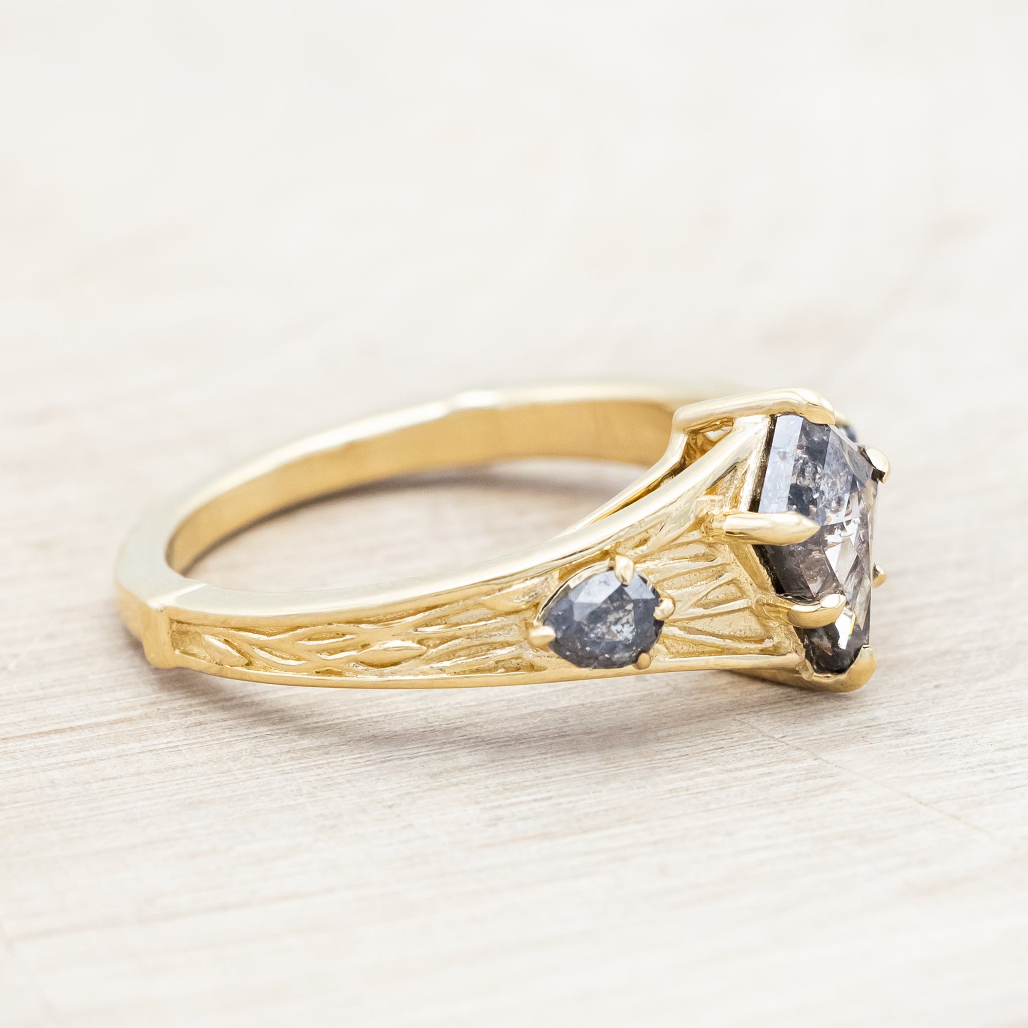 14K gold ring with salt & pepper diamond on a wooden surface