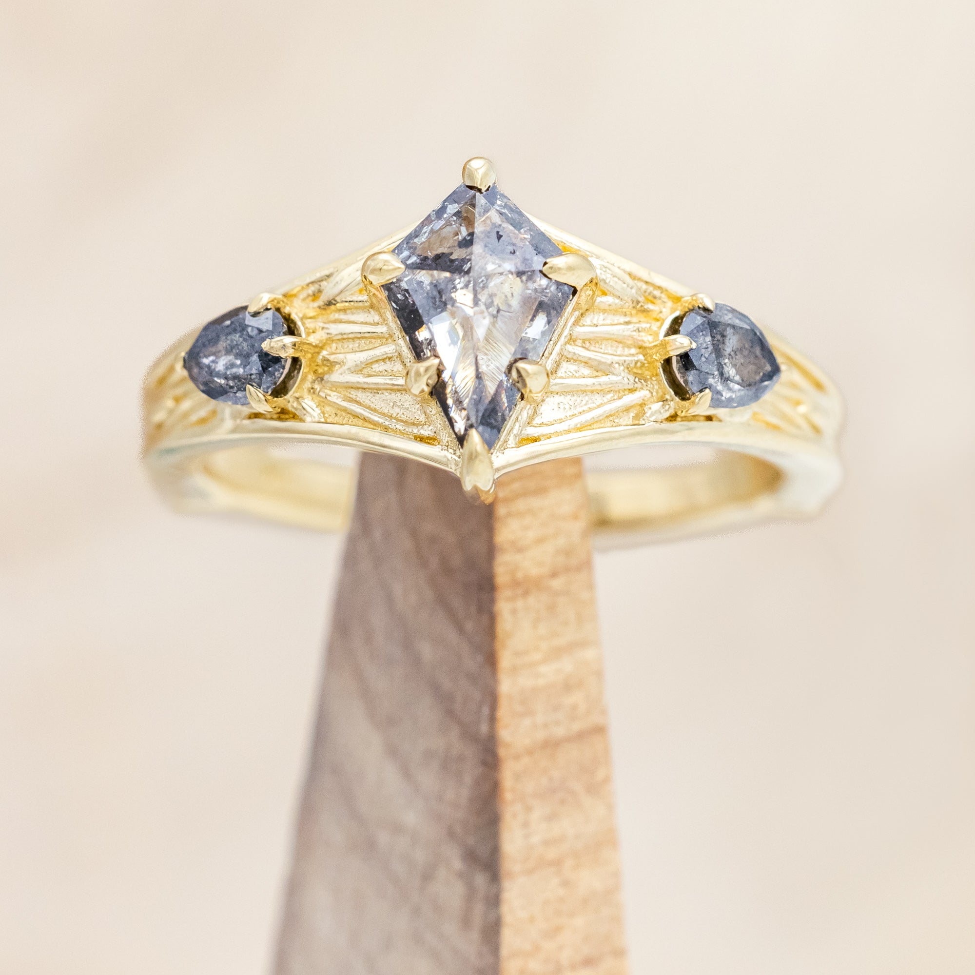 14K gold ring with salt & pepper diamond on a wooden stand against a beige background