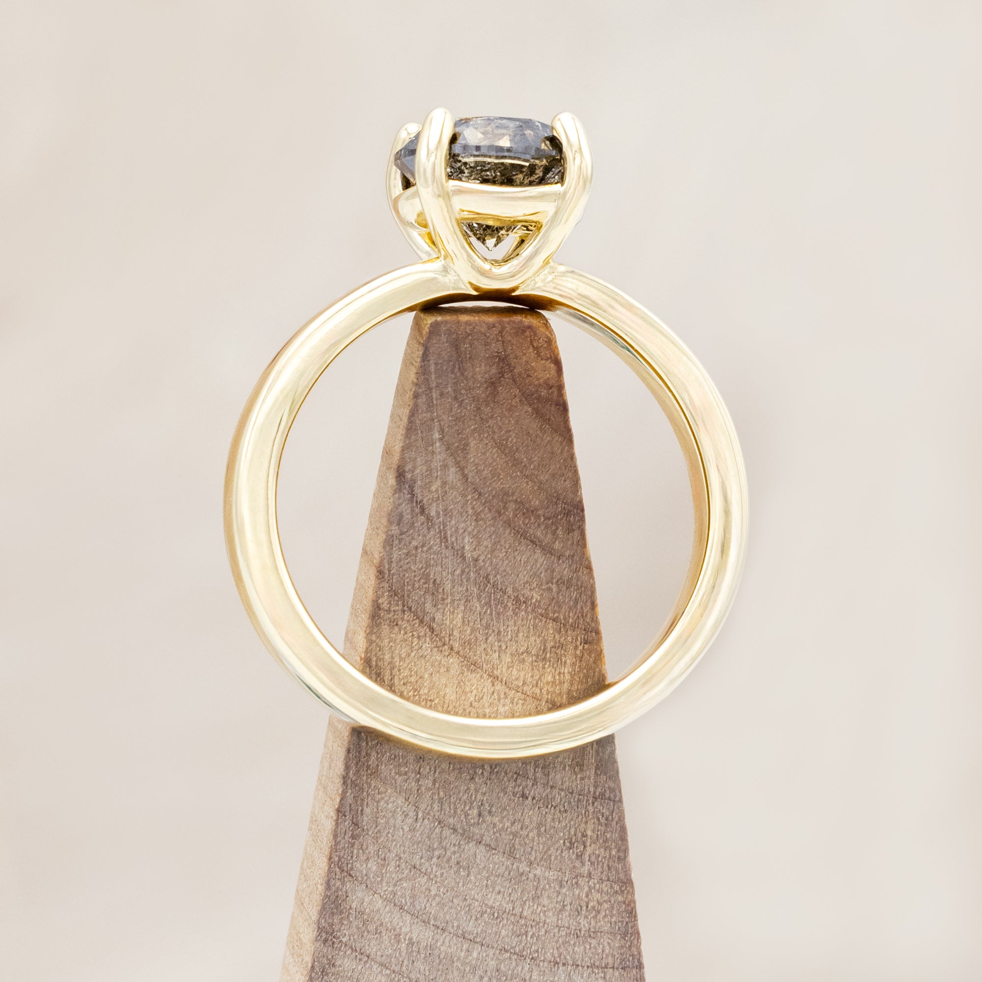 Wide 14K gold ring with a salt & pepper diamond on a beige background