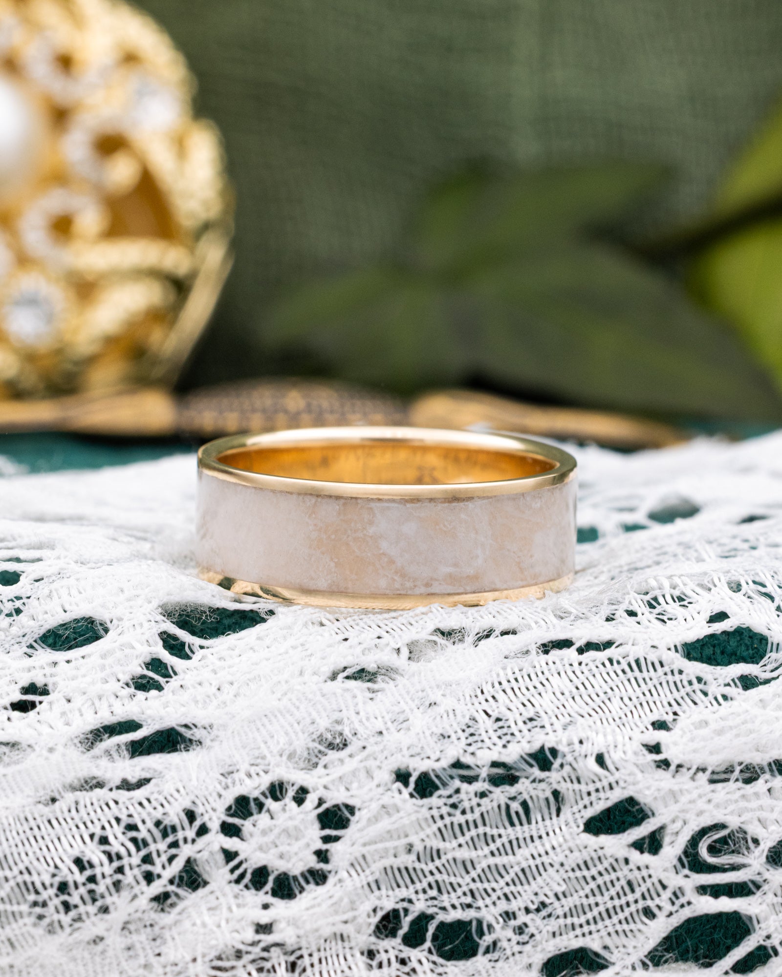 Gold ring on a white lace fabric with a blurred green background