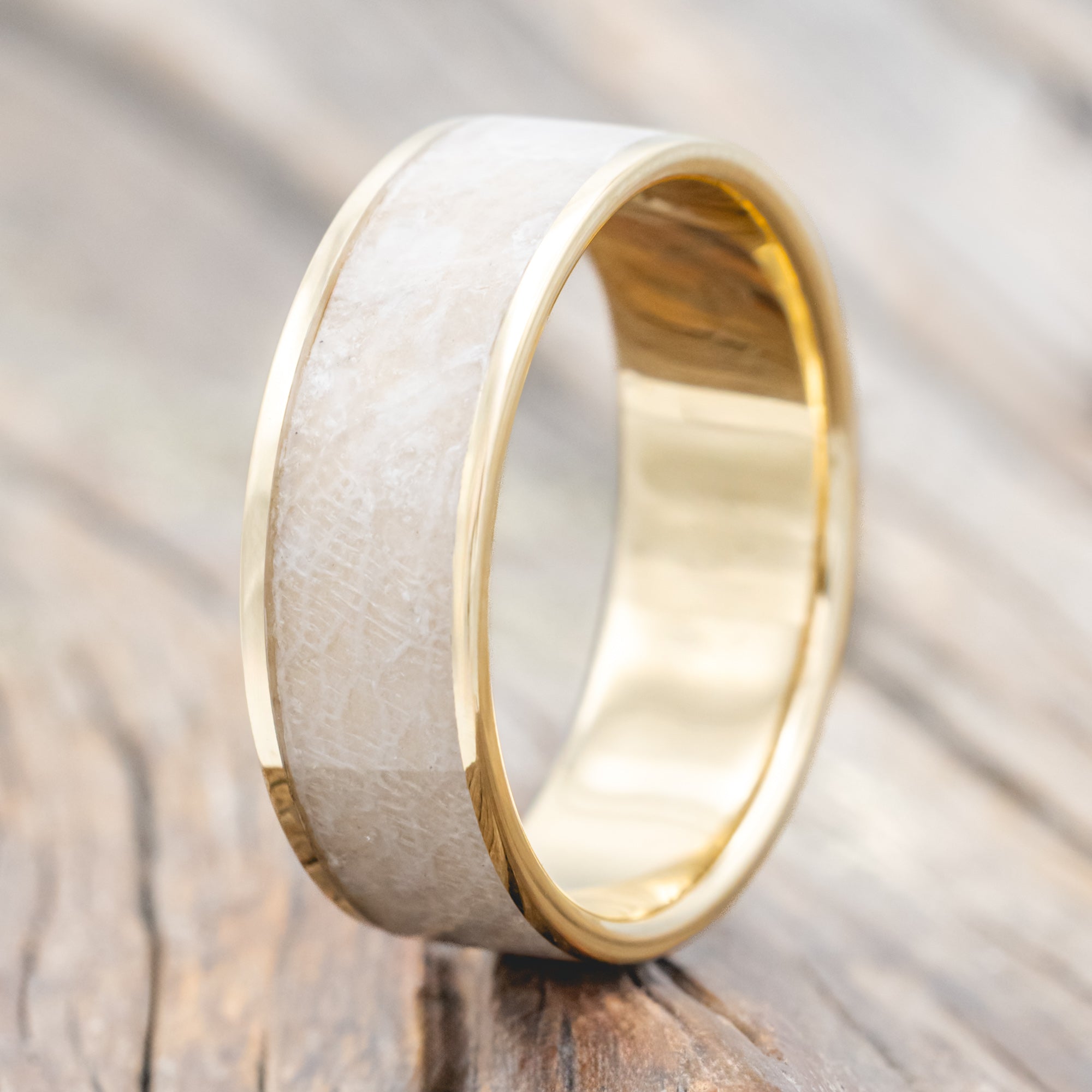 Gold ring with wedding dress inlay on a wooden surface