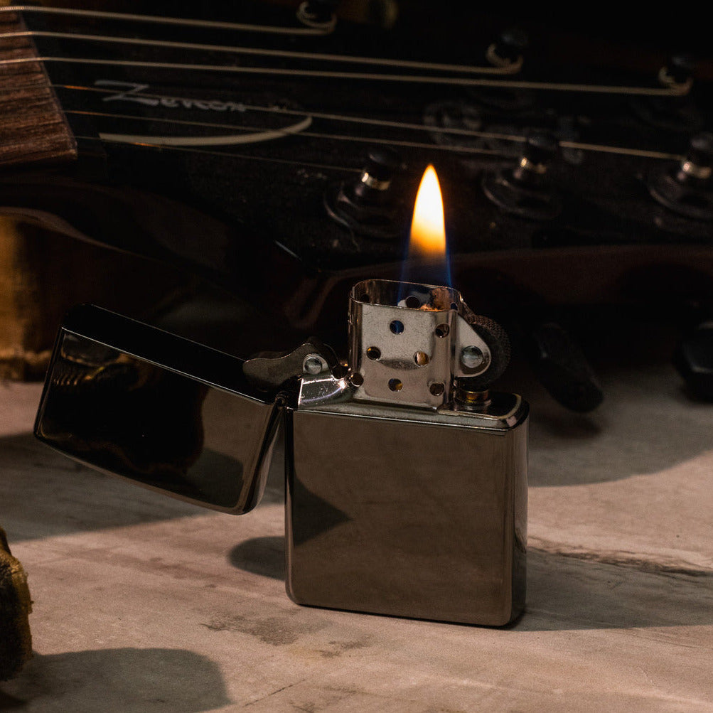 Zippo lighter with flame on a wooden surface with a blurred natural background