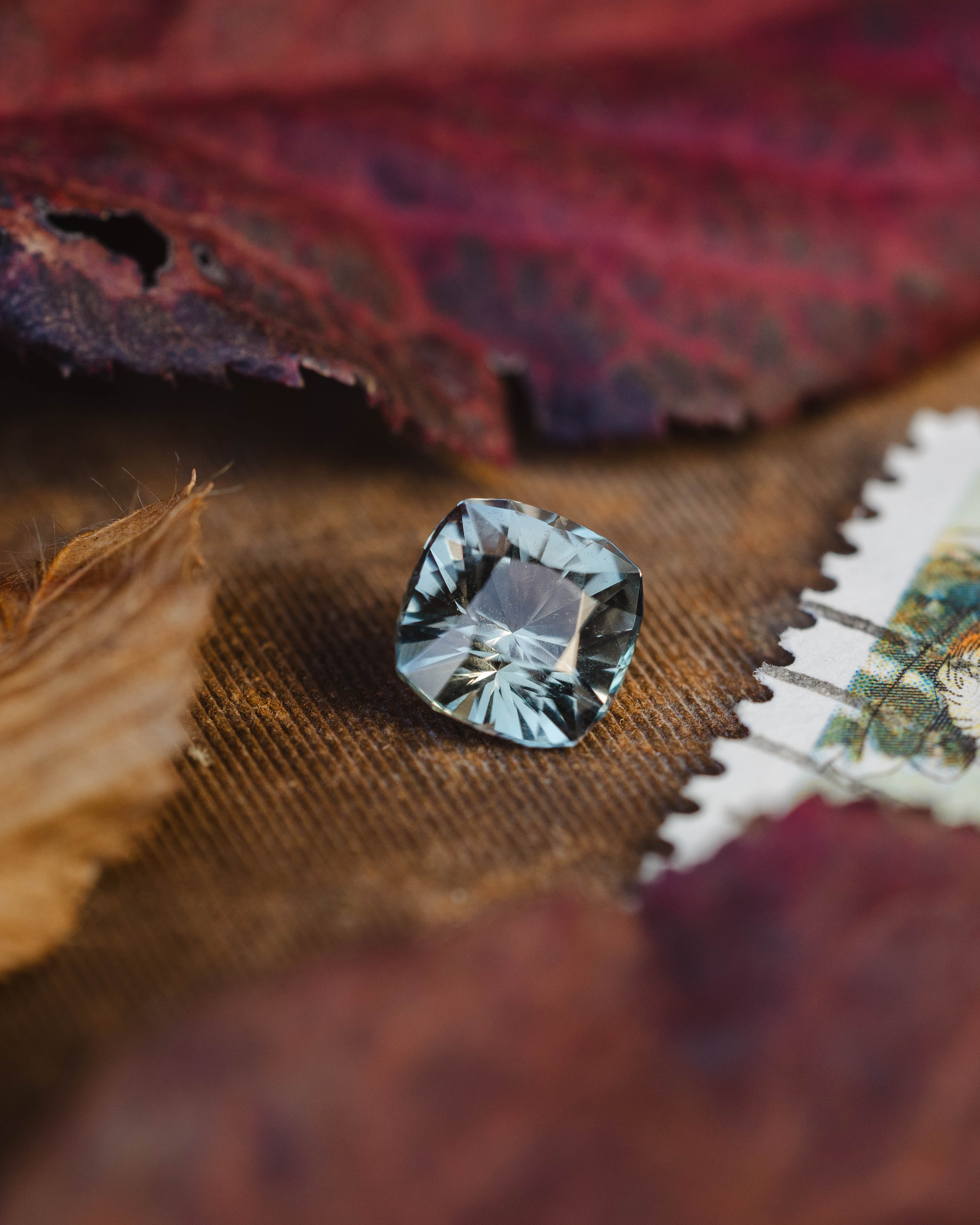 Faceted silver sapphire on a textured fabric background