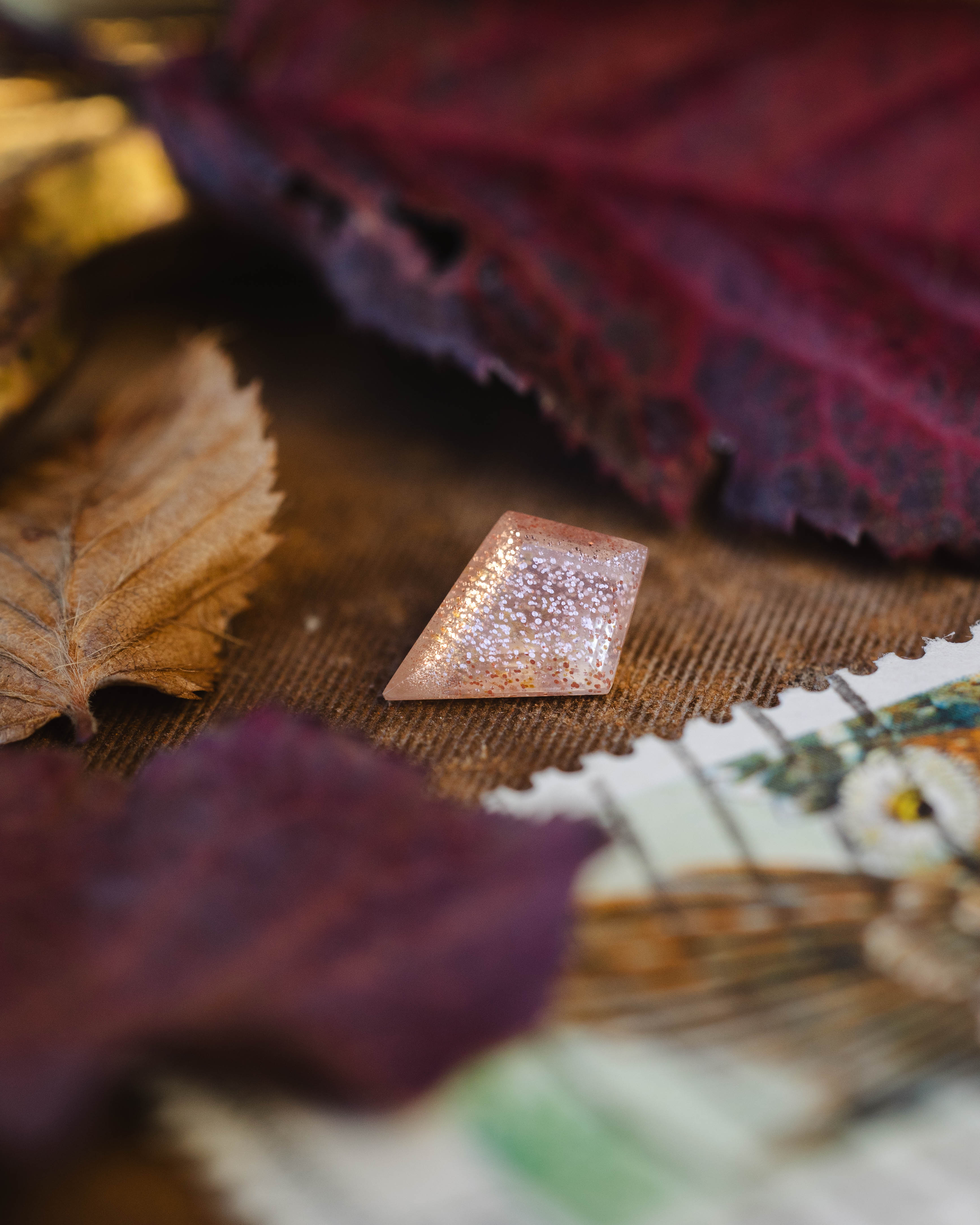 Kite cut sunstone on a textured surface with leaves