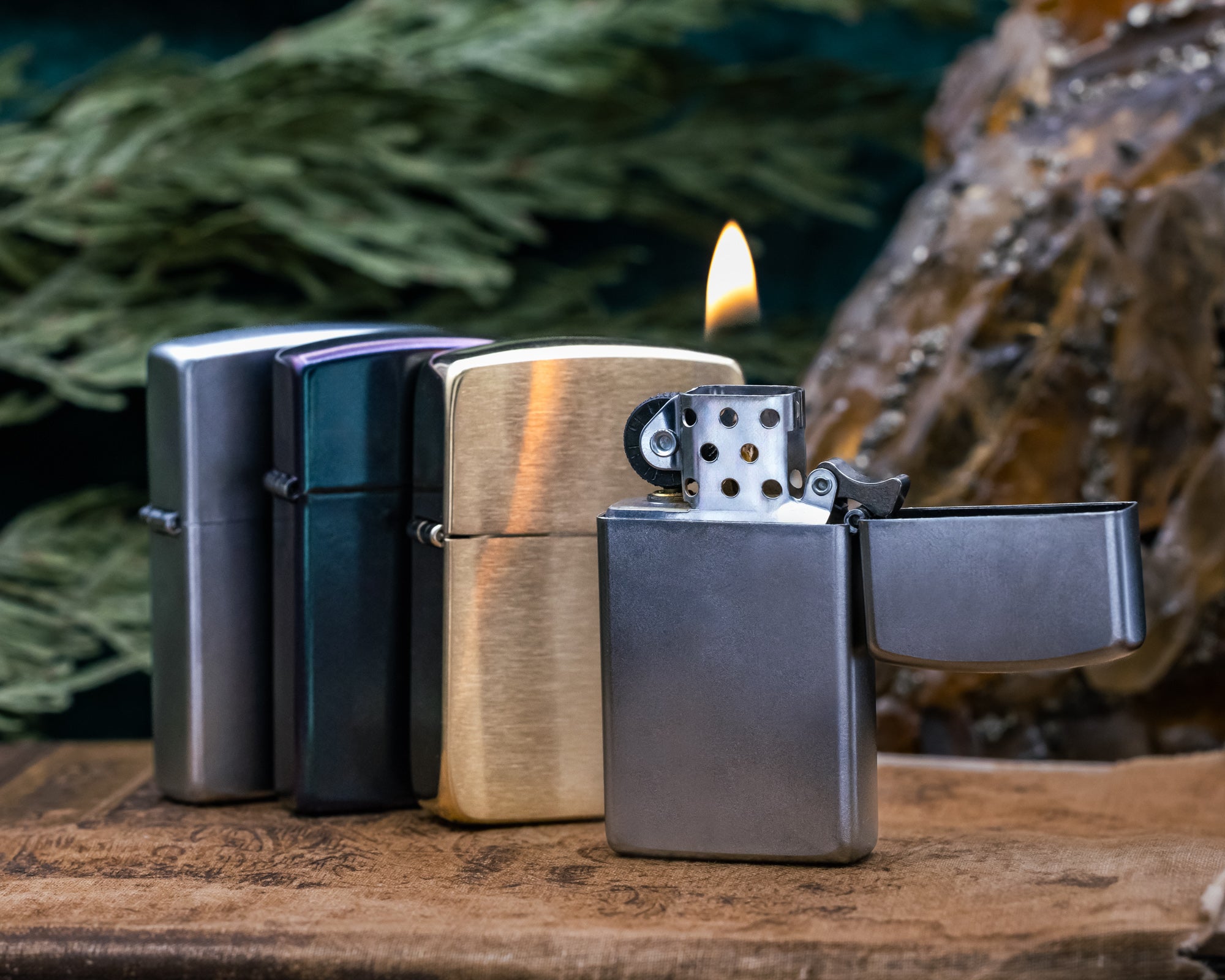 Four zippo lighters on a wooden surface with a blurred natural background