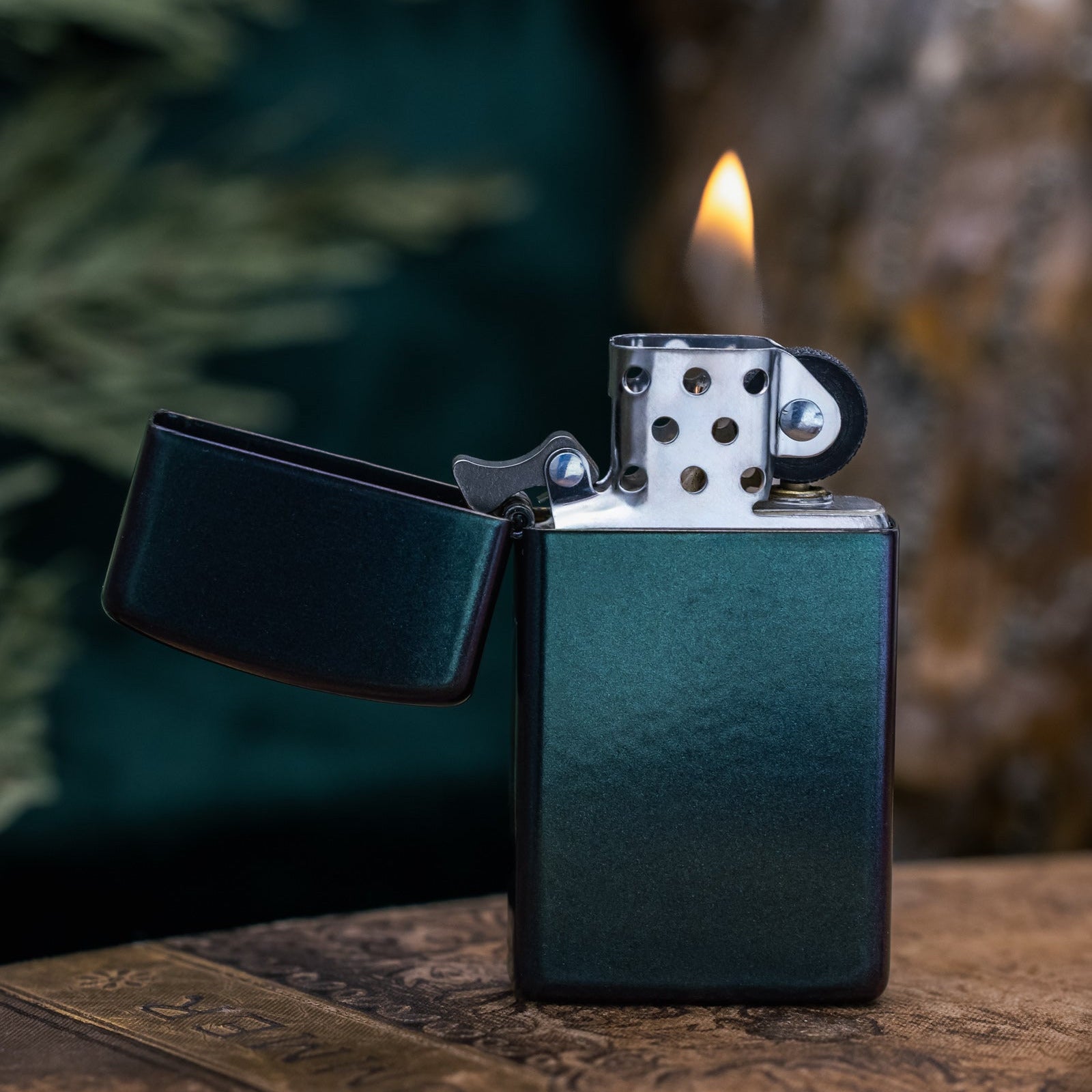 Zippo lighter with flame on a wooden surface with a blurred natural background