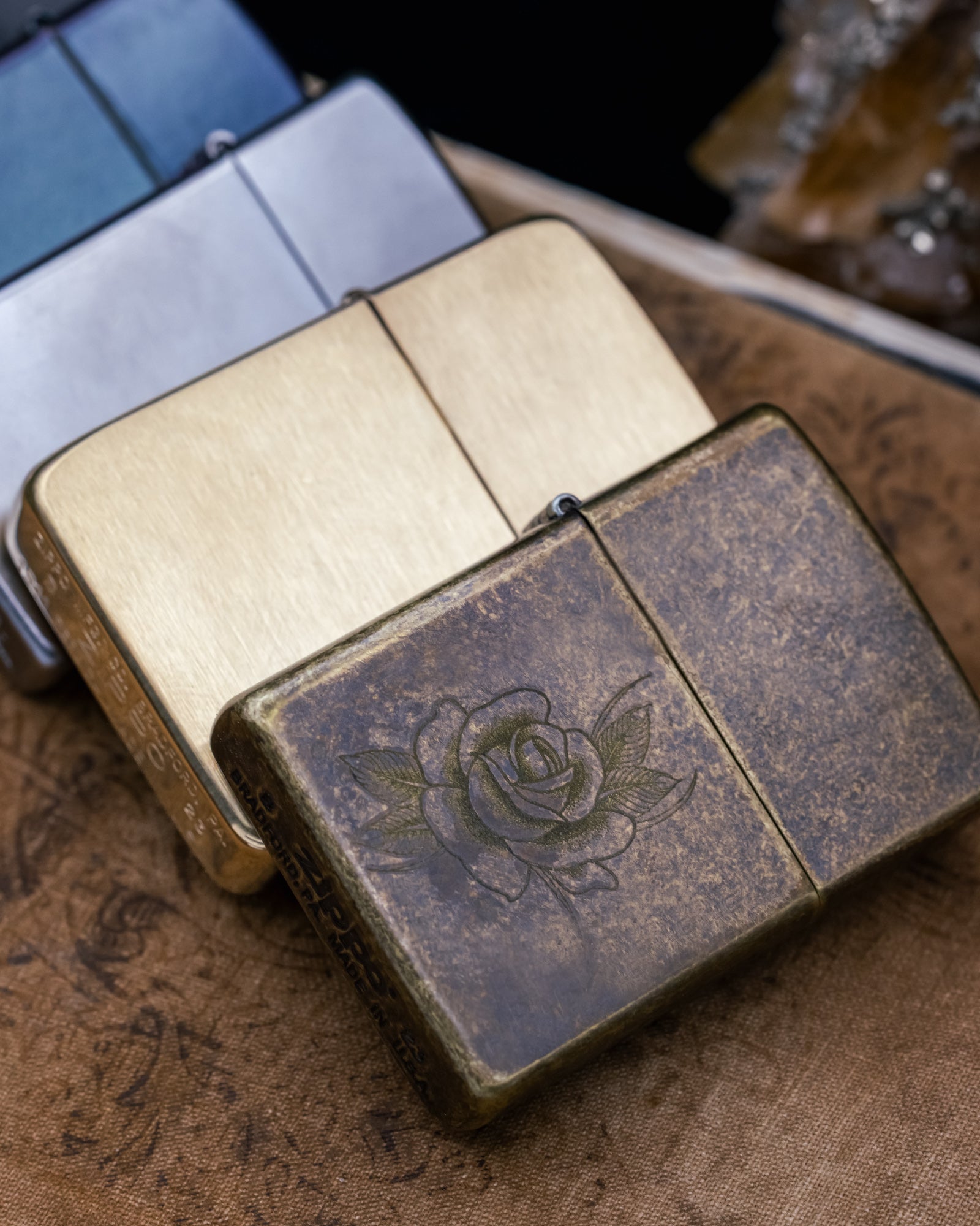Multiple Zippo lighters on a wooden surface.