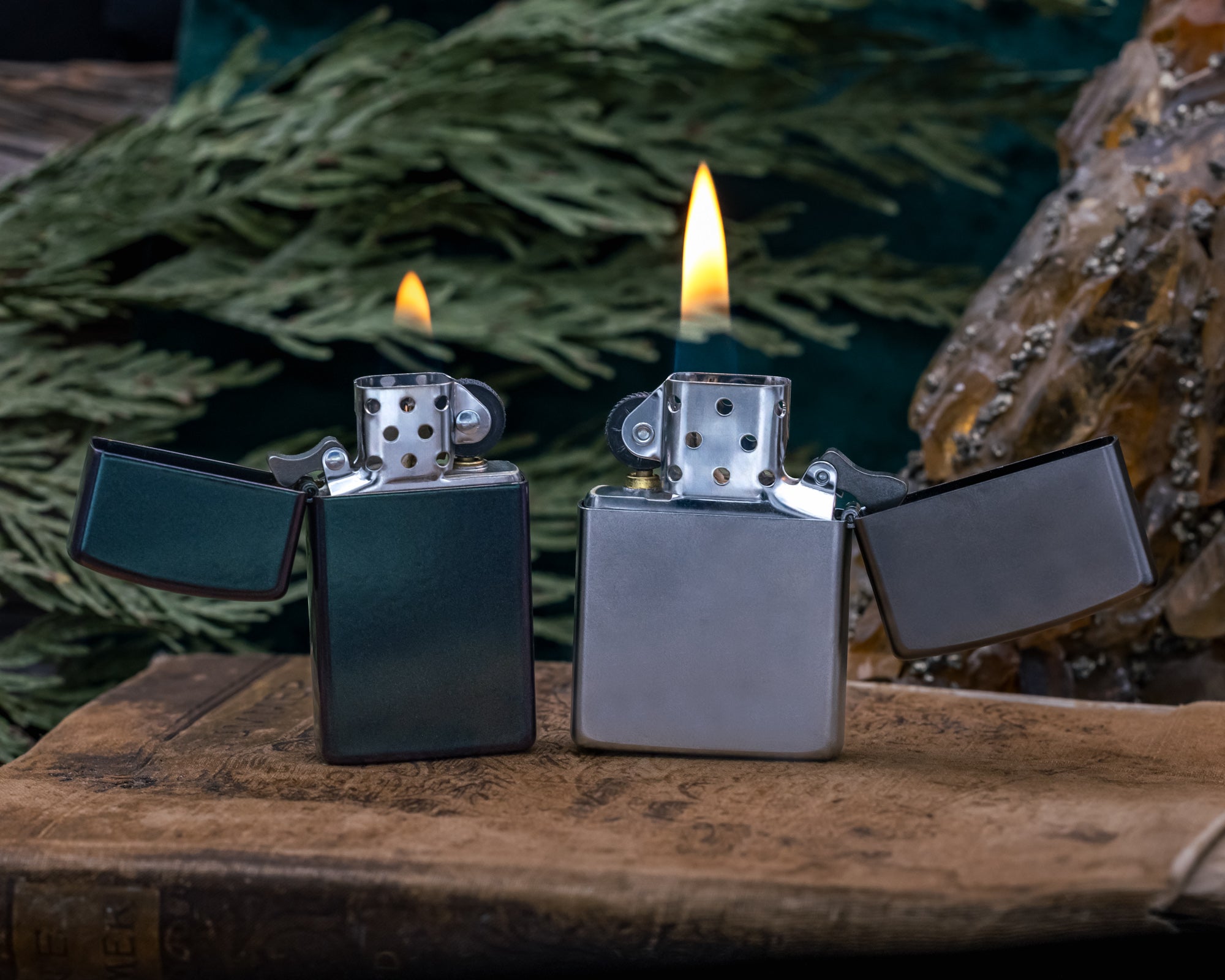Two Zippo lighters on a wooden surface with a blurred natural background