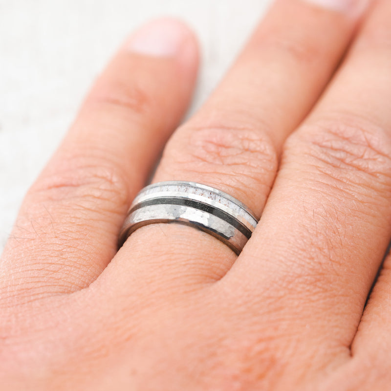 Shown here, Cosmo, a custom, handcrafted men's wedding ring featuring iron ore and antler inlays, shown here on a hammered titanium band, on hand. Additional inlay options are available upon request.