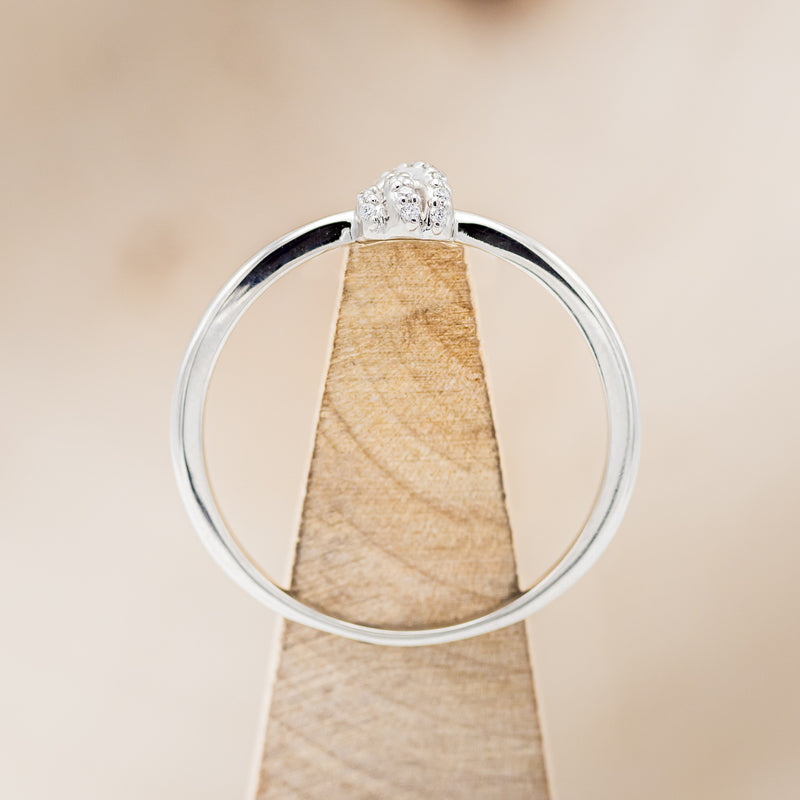 Shown here is a dainty-style knot women's stacking band with diamond accents, side view on stand.