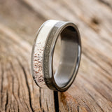 Shown here is "Raptor", a custom, handcrafted men's wedding ring featuring elk antler and iron ore inlays, upright facing left. Additional inlay options are available upon request.