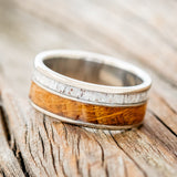 Shown here is "Raptor", a custom, handcrafted men's wedding ring featuring authentic whiskey barrel oak and elk antler inlays, tilted left. Additional inlay options are available upon request.
