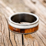 Shown here is "Raptor", a custom, handcrafted men's wedding ring featuring granite and redwood inlays, laying flat. Additional inlay options are available upon request.