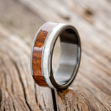 Shown here is "Raptor", a custom, handcrafted men's wedding ring featuring granite and redwood inlays, upright facing left. Additional inlay options are available upon request.