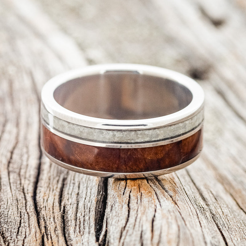 Shown here is "Raptor", a custom, handcrafted men's wedding ring featuring granite and redwood inlays on a titanium band, laying flat. Additional inlay options are available upon request.