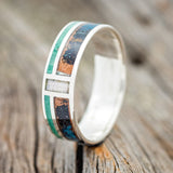 Shown here is "Bower", a custom, handcrafted men's wedding ring featuring a patina copper, malachite, and mother of pearl inlays, upright facing left. Additional inlay options are available upon request.
