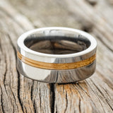 Shown here is "Vertigo", a custom, handcrafted men's wedding ring featuring a whiskey barrel inlay, laying flat. Additional inlay options are available upon request.