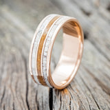 Shown here is "Rio", a custom, handcrafted men's wedding ring featuring 3 channels with whiskey barrel oak and antler inlays on a 14K gold band, upright facing left. Additional inlay options are available upon request.