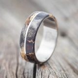 Shown here is "Golden", a custom, handcrafted men's wedding ring featuring a buckeye burl wood overlay with gold nuggets set in the burls, upright facing left. Additional inlay options are available upon request.