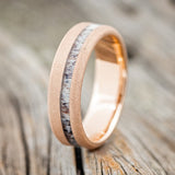 Shown here is "Vertigo", a custom, handcrafted men's wedding ring featuring an offset antler inlay on a sandblasted 14K gold band, upright facing left. Additional inlay options are available upon request.