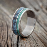 Shown here is "Raptor", a custom, handcrafted men's wedding ring featuring a patina copper and malachite inlay, upright facing left.