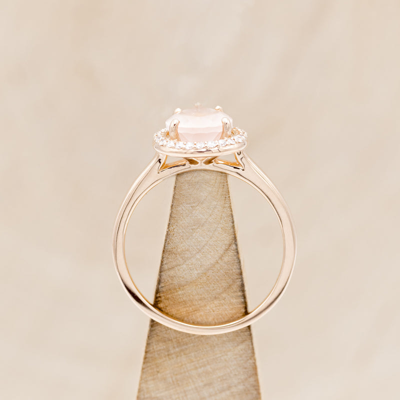 Shown here is "Clariss", a rose quartz women's engagement ring with a diamond halo, side view on stand. Many other center stone options are available upon request.