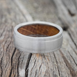 Shown here is "Sedona", a handcrafted whiskey barrel-lined men's wedding ring, featuring a brushed finish, laying flat. Additional inlay options are available upon request.