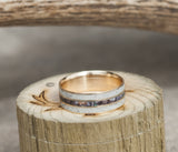 Shown here is "Rio", a custom, handcrafted men's wedding ring featuring 3 channels with antler and camo inlays, laying flat. Additional inlay options are available upon request.