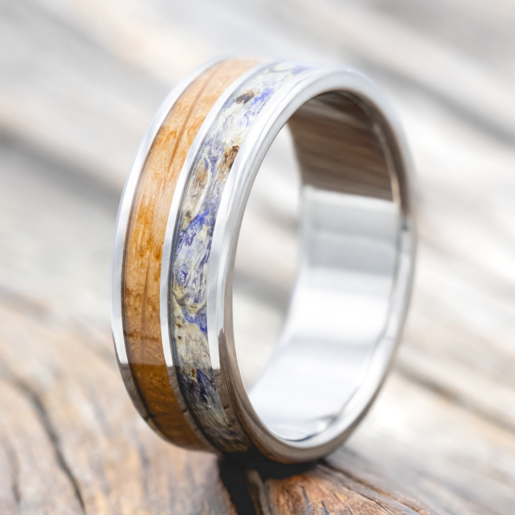 Titanium ring with whiskey barrel oak and bluebell inlay on a wooden surface