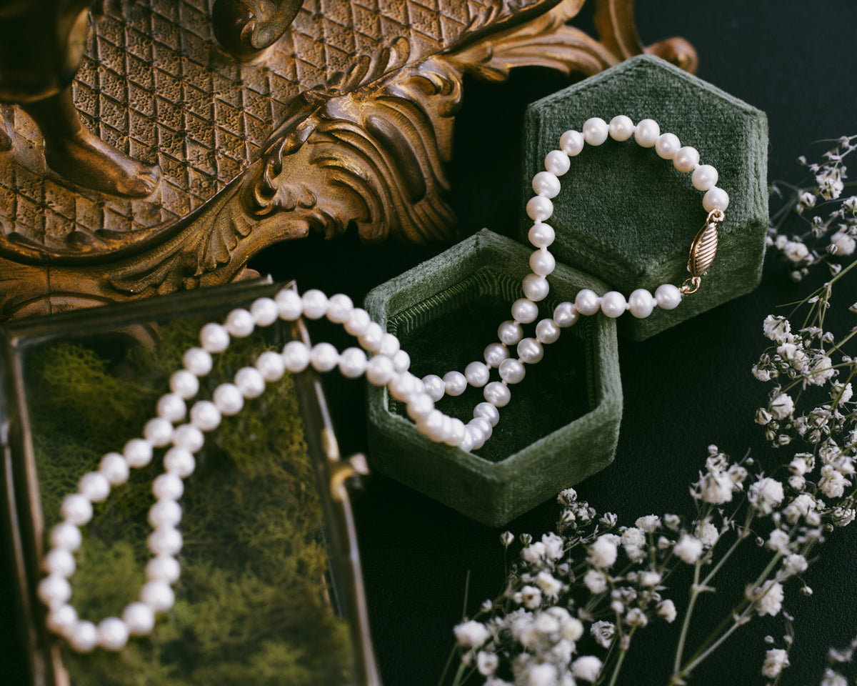 Pearl necklace in a green jewelry box against a floral background