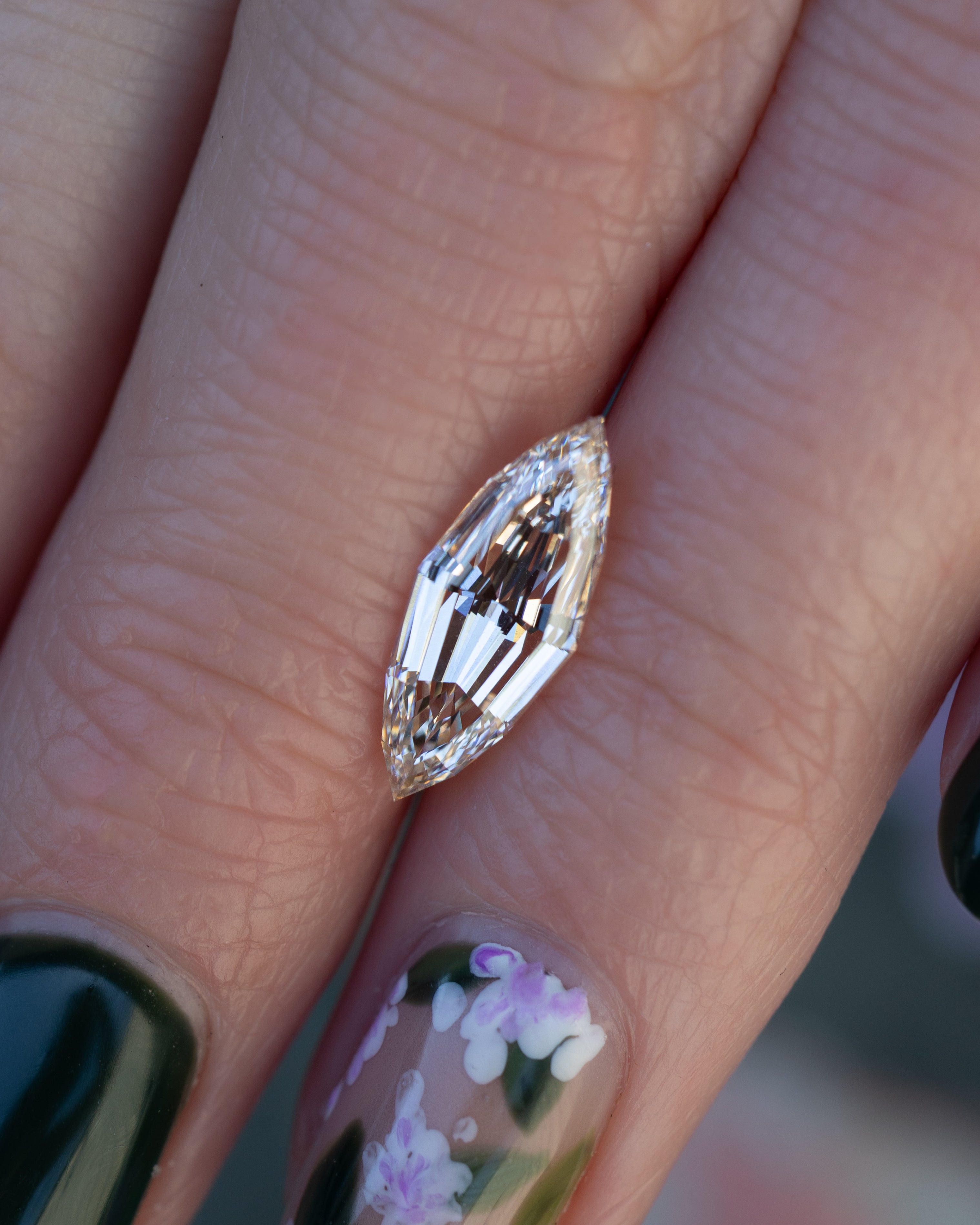 Close-up of fingers holding a marquise champagne diamond.