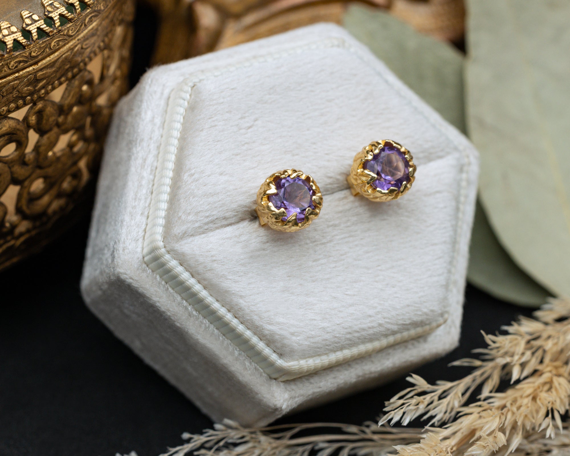 Pair of purple amethyst earrings in a hexagonal white jewelry box.