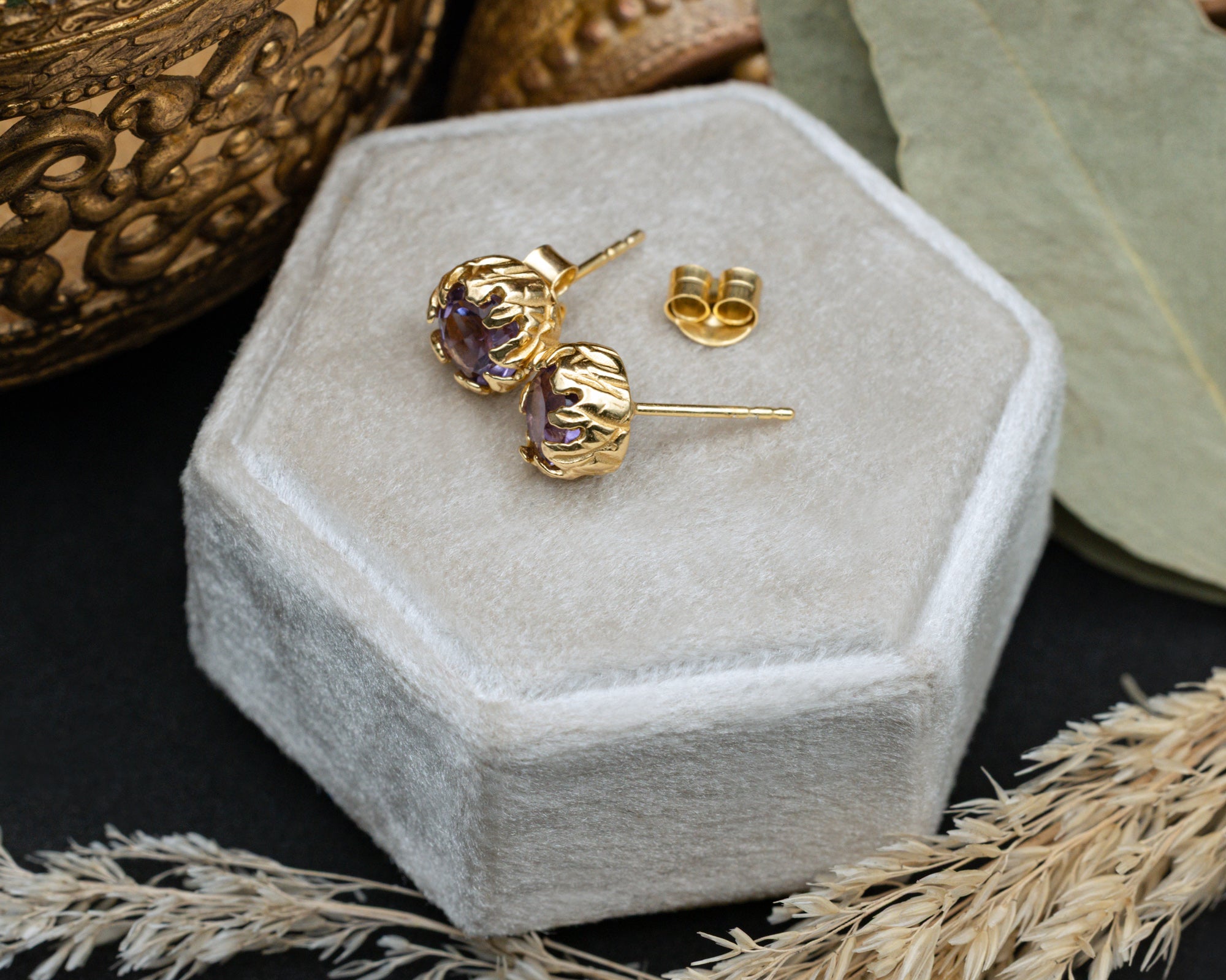 Pair of purple amethyst earrings in a hexagonal white jewelry box.