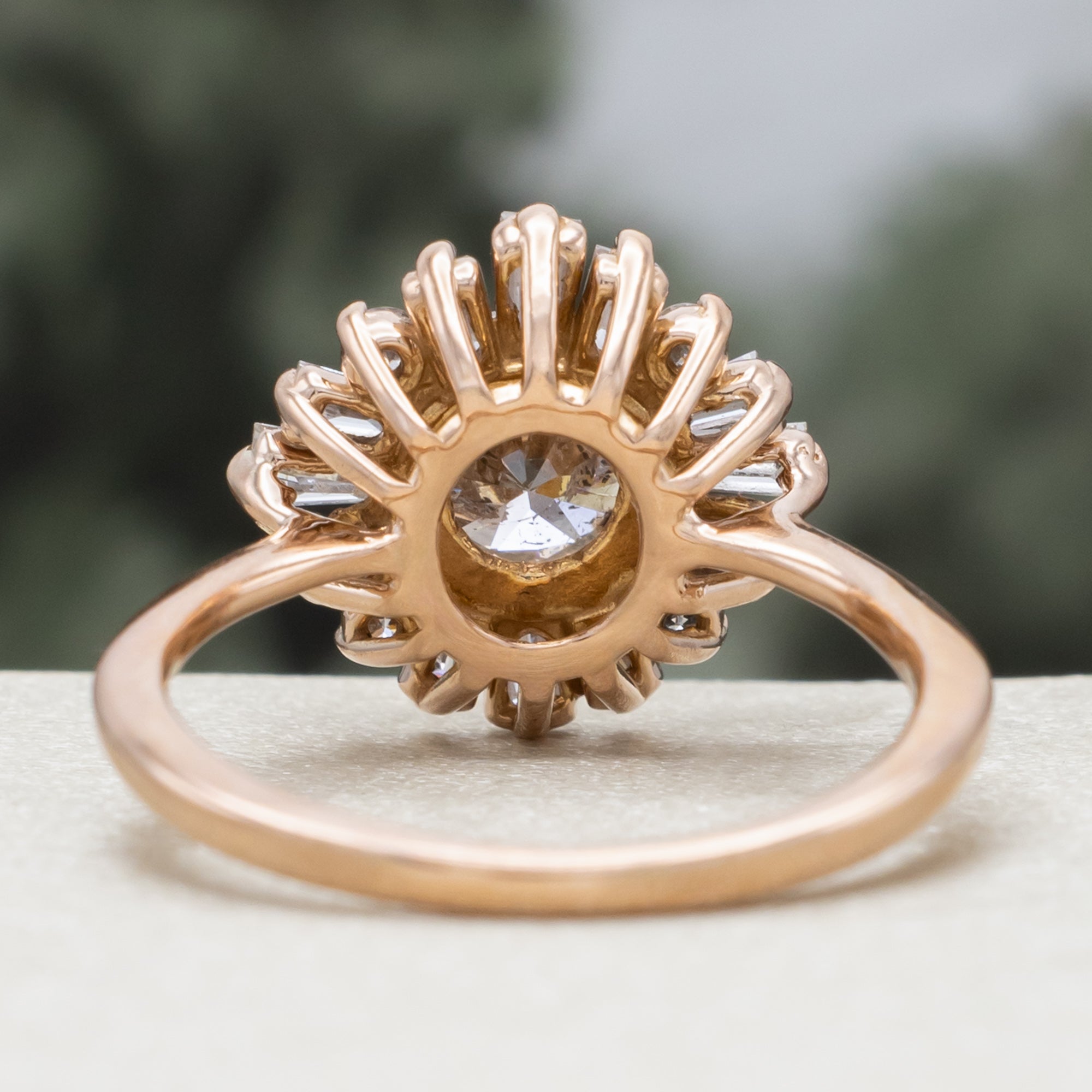 Rose gold champagne diamond engagement ring with diamond halo against a blurred green background