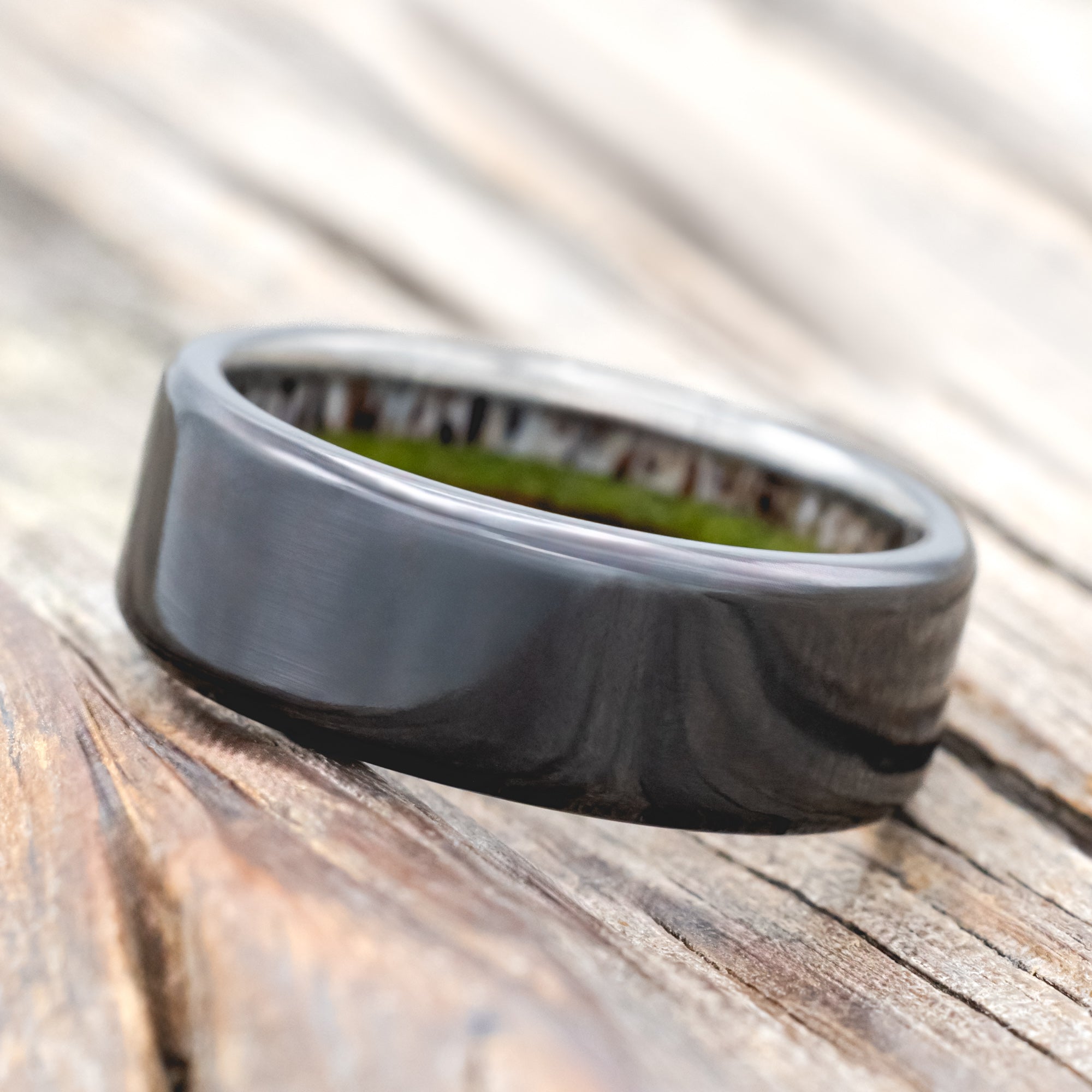 Black zirconium ring with antler, ironwood and moss lining on wood background