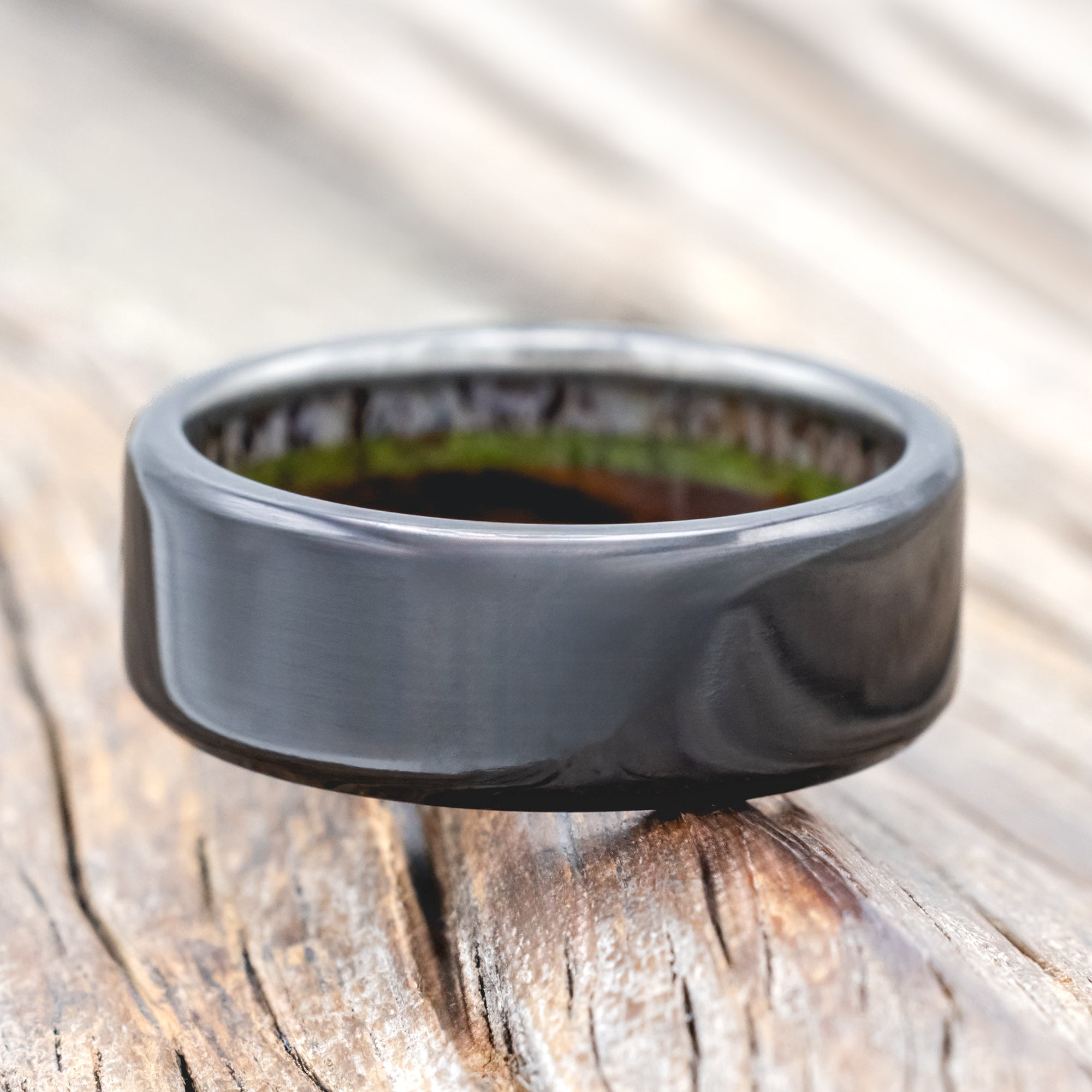 Black zirconium ring with antler, ironwood and moss lining on wood background