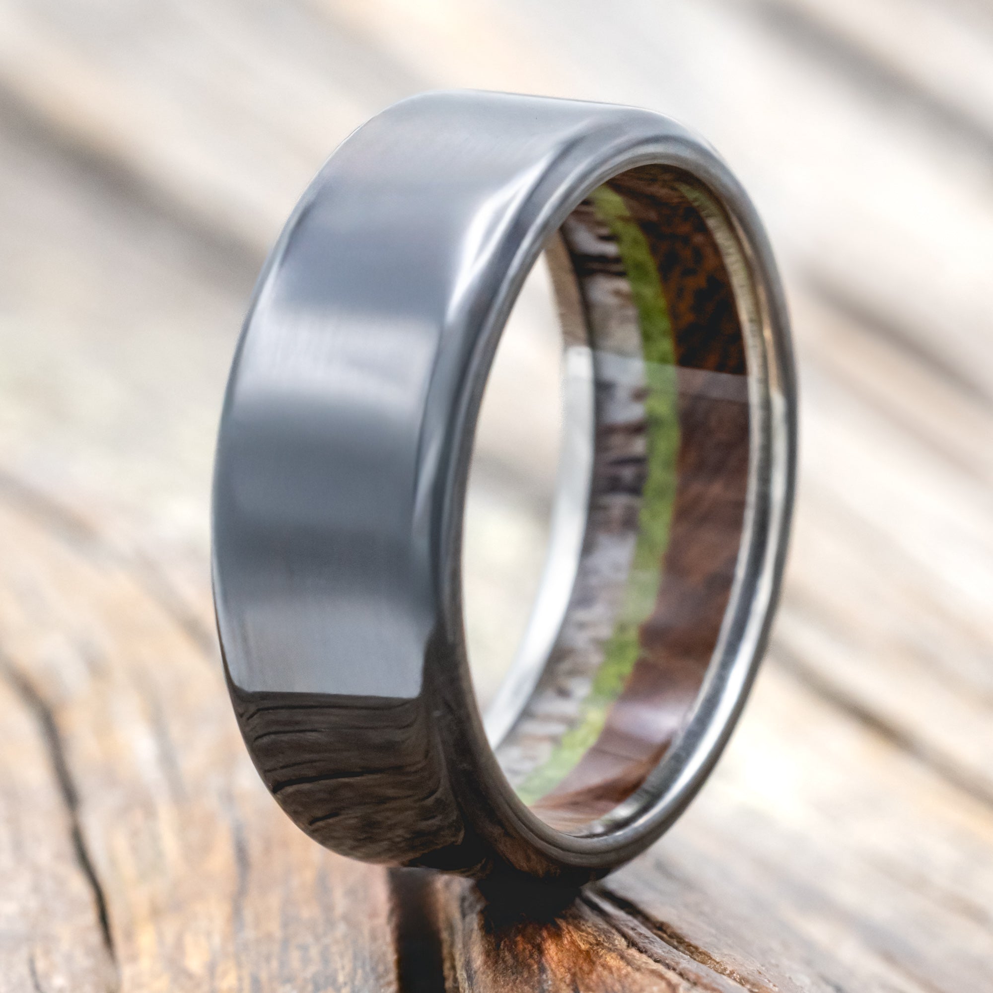 Black zirconium ring with antler, ironwood and moss lining on wood background