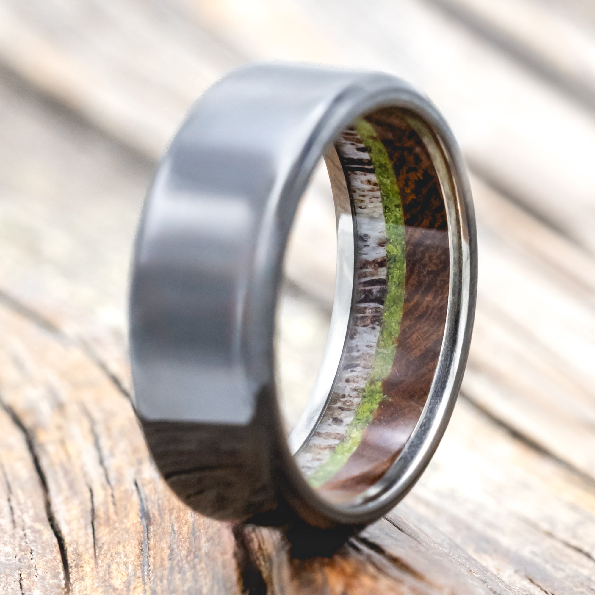 Black zirconium ring with antler, ironwood and moss lining on wood background