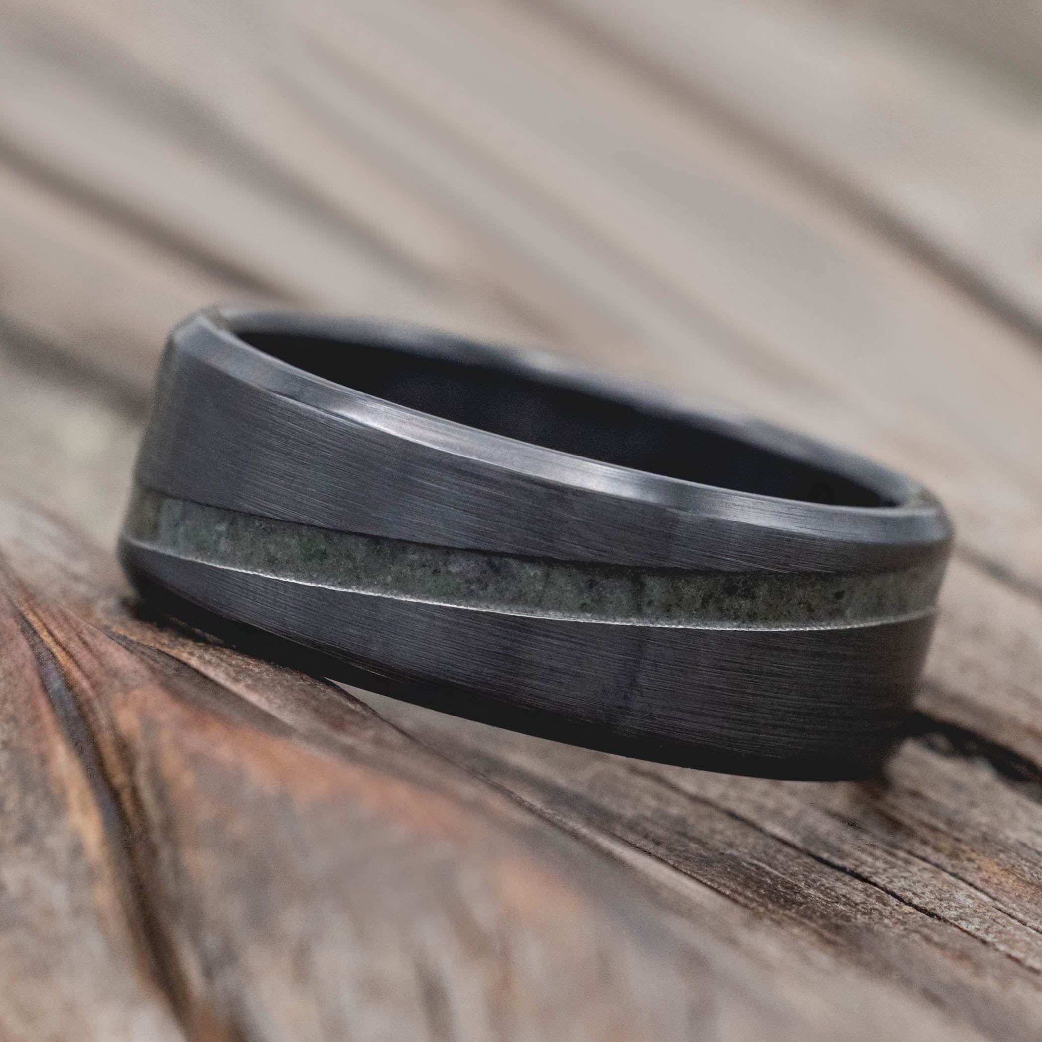 Black zirconium ring with a textured band on a wooden surface