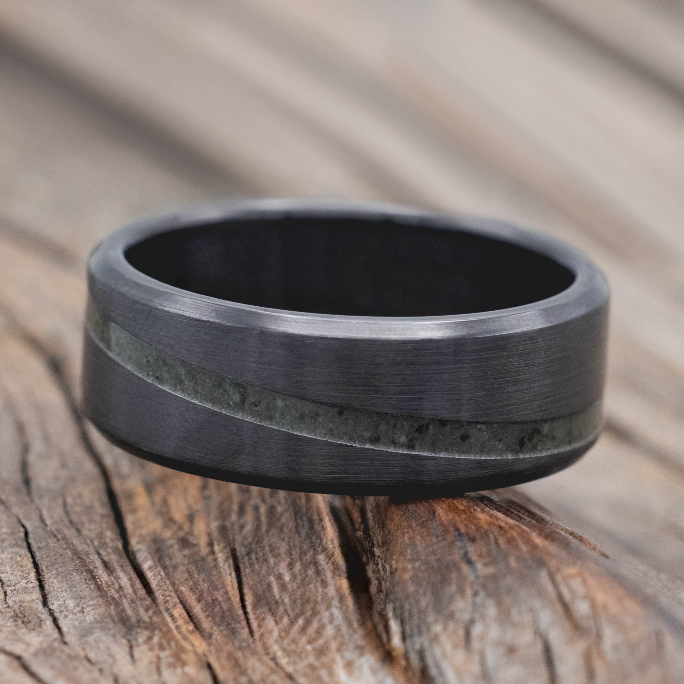 Black zirconium ring with a textured band on a wooden surface