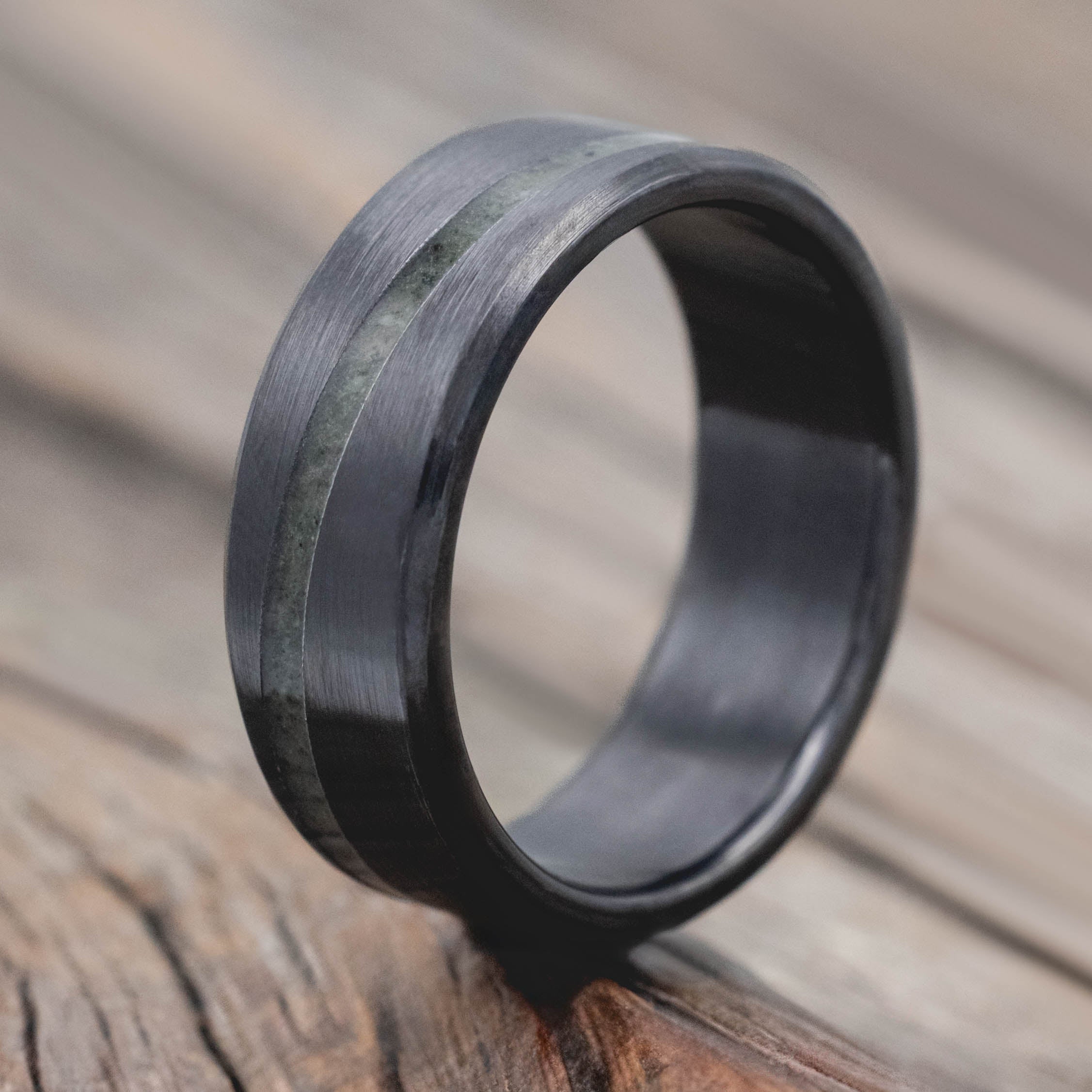 Black zirconium ring with a textured band on a wooden surface