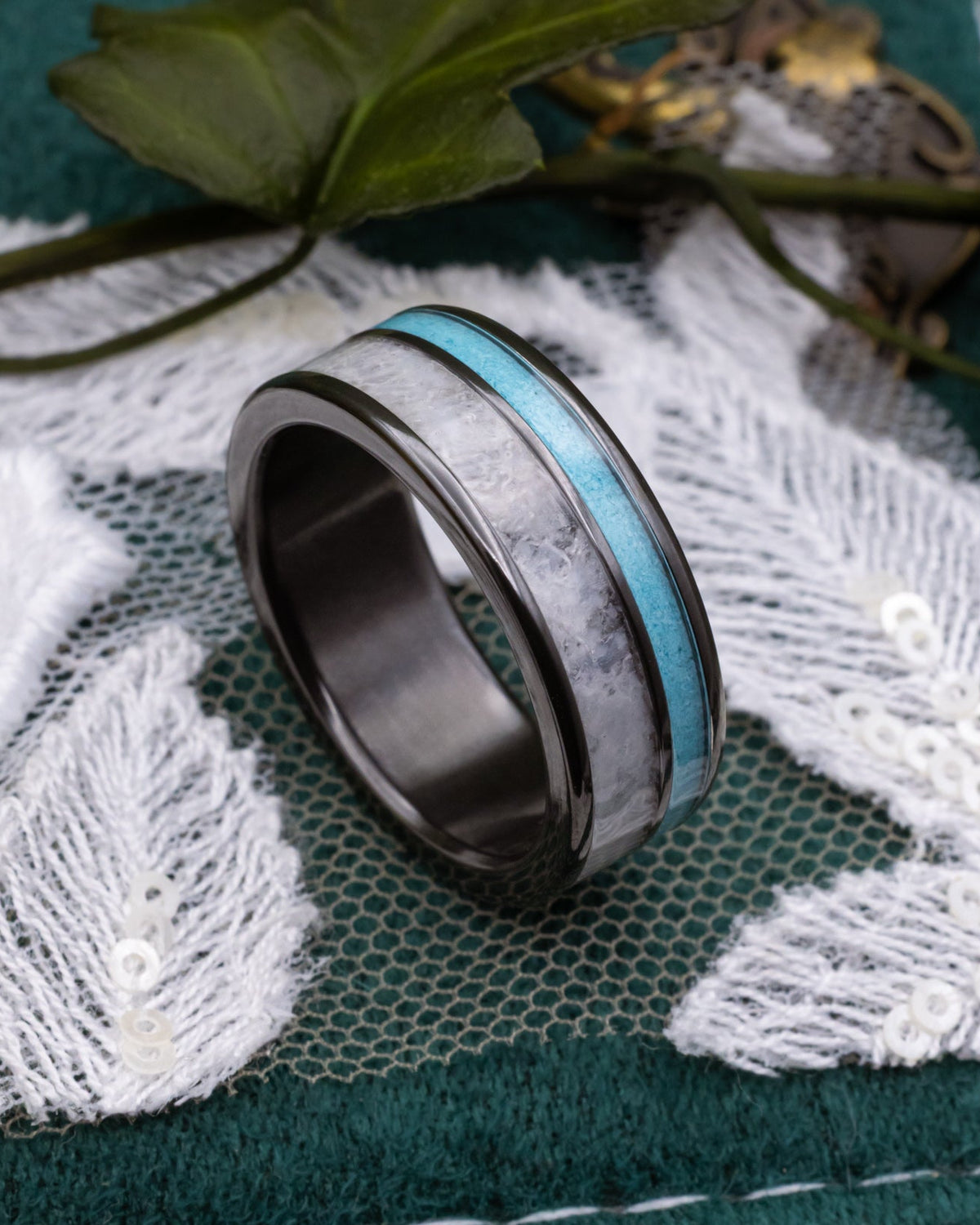 Black zirconium ring with turquoise and wedding dress inlay on a lace and decorative background