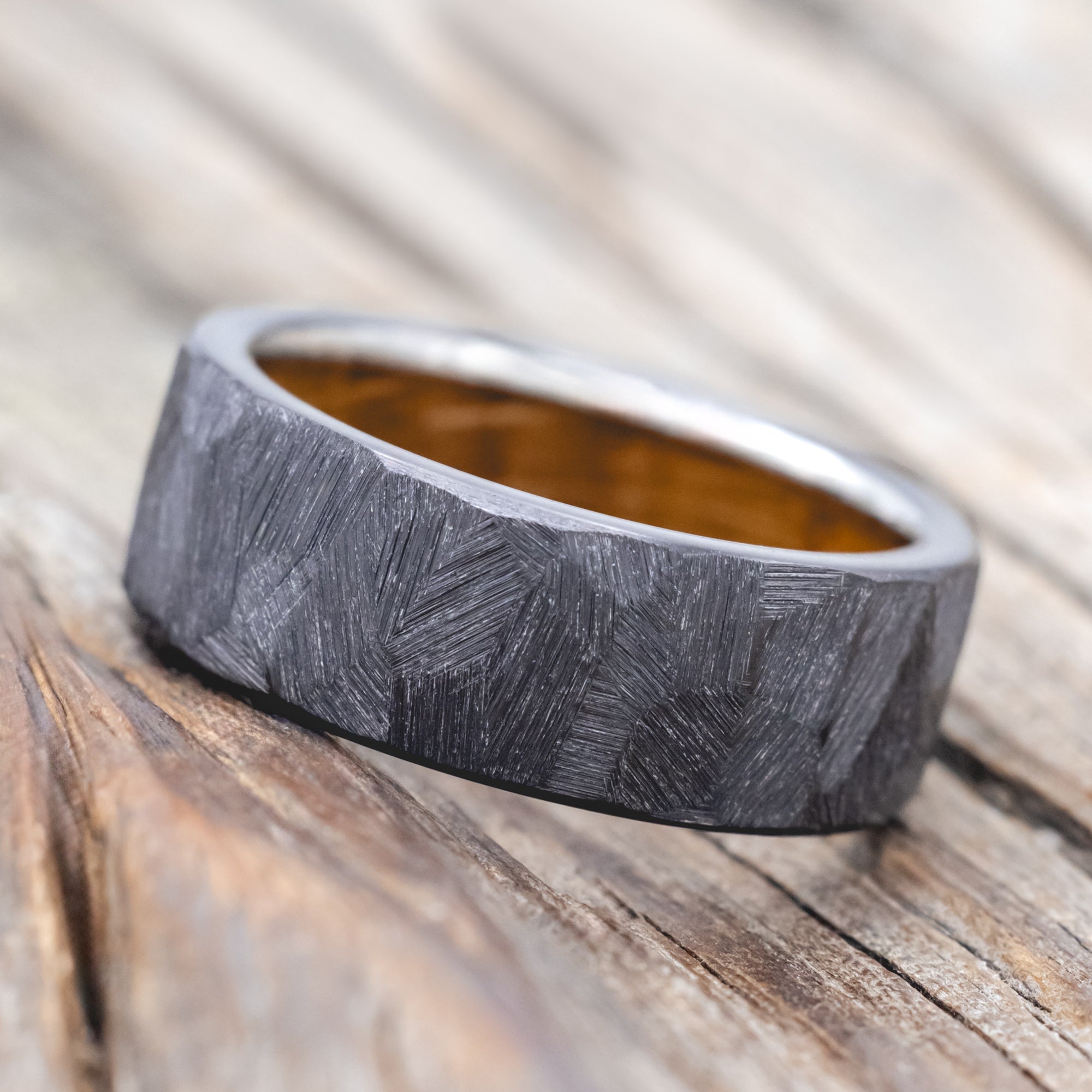 Faceted band with whiskey barrel oak lining on a wooden background