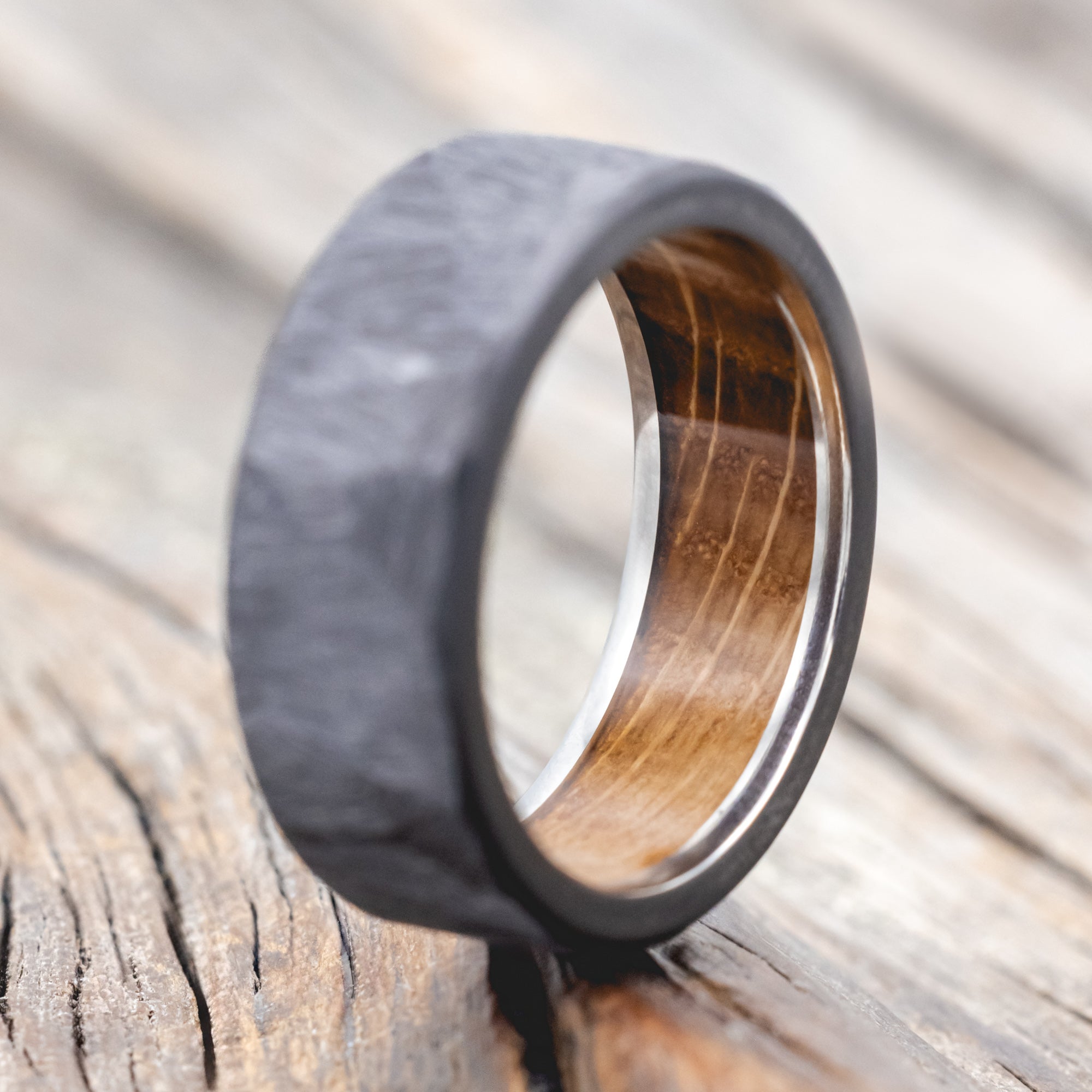 Faceted band with whiskey barrel oak lining on a wooden background