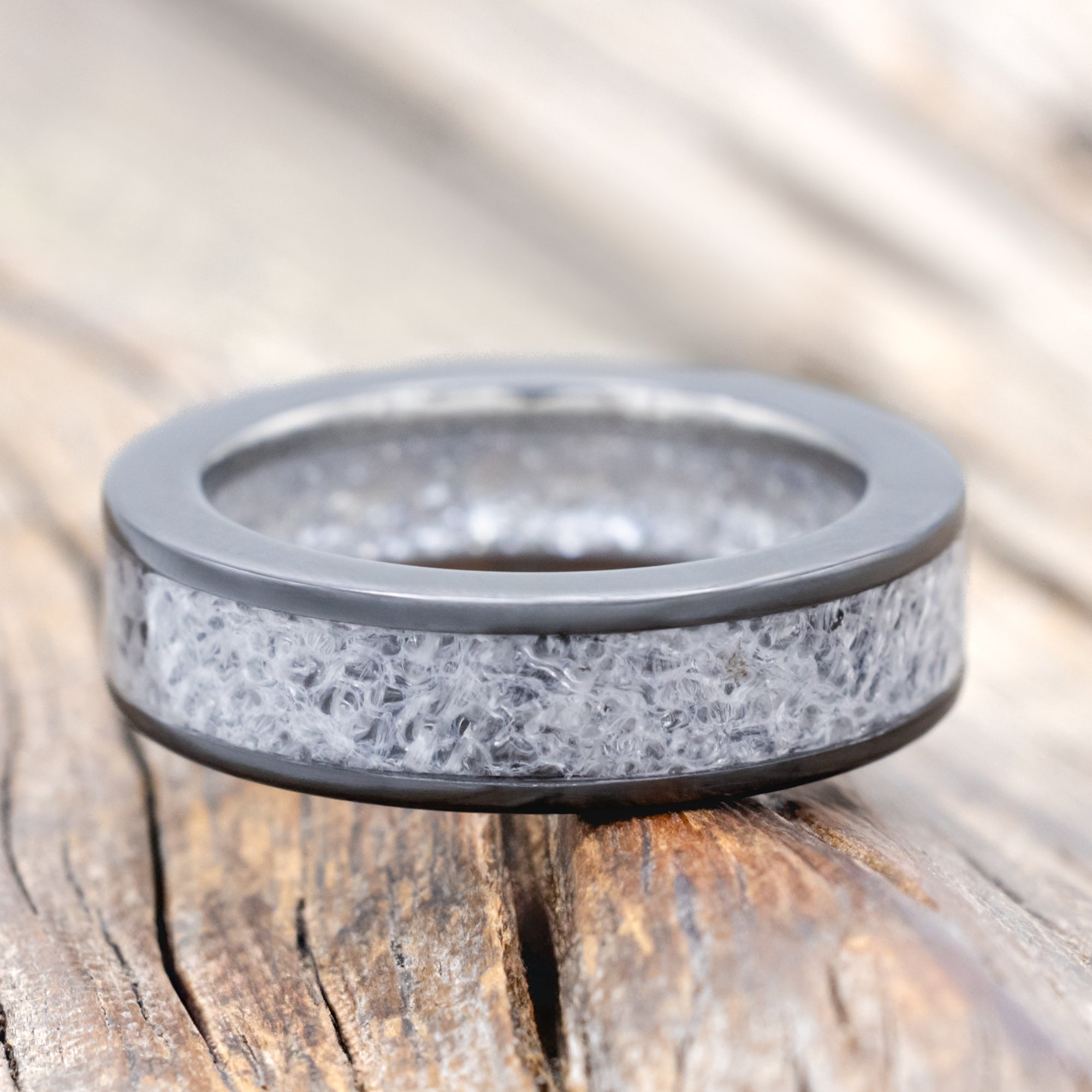 Black zirconium band with wedding dress inlay & diamond dust lining on a wooden surface