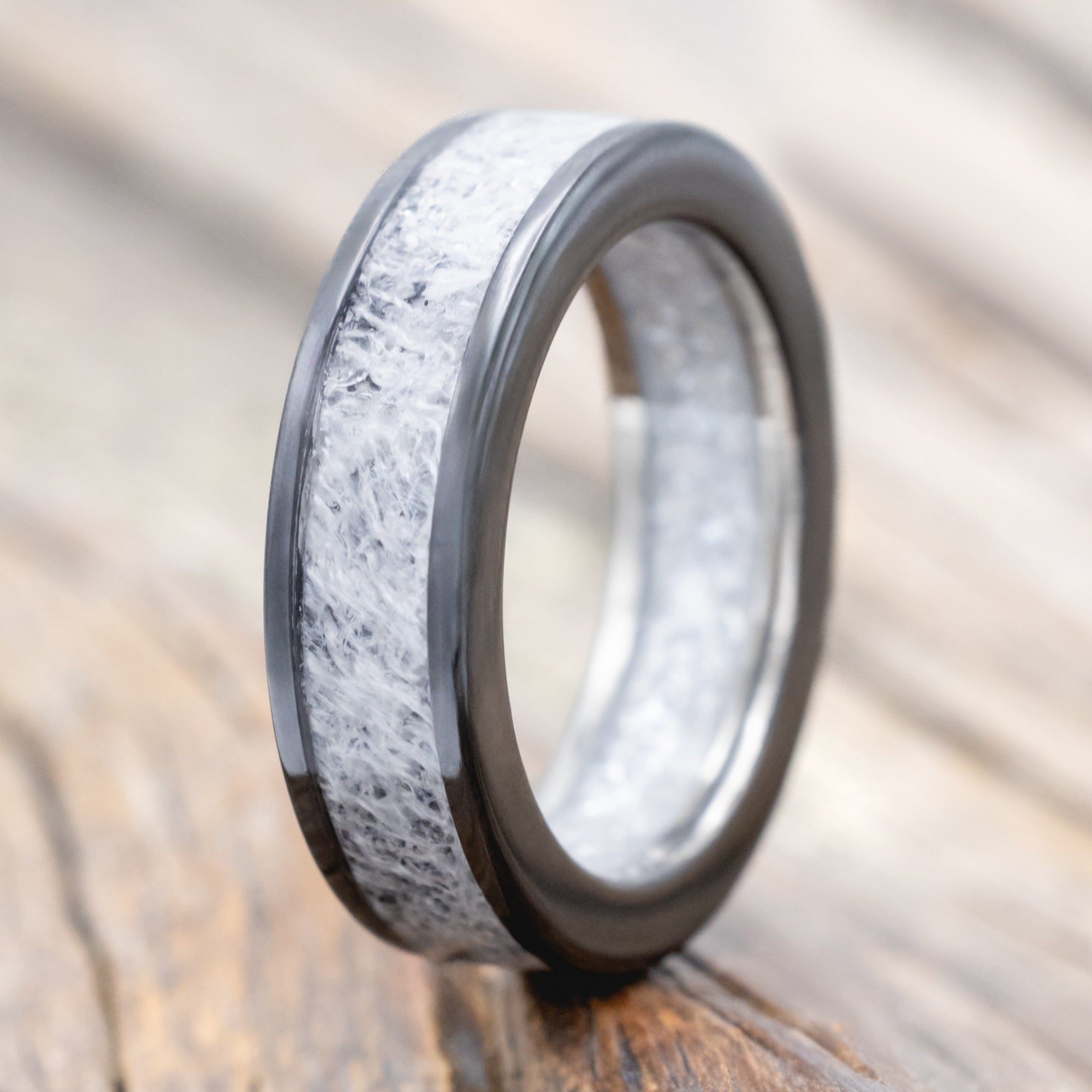 Black zirconium band with wedding dress inlay & diamond dust lining on a wooden surface