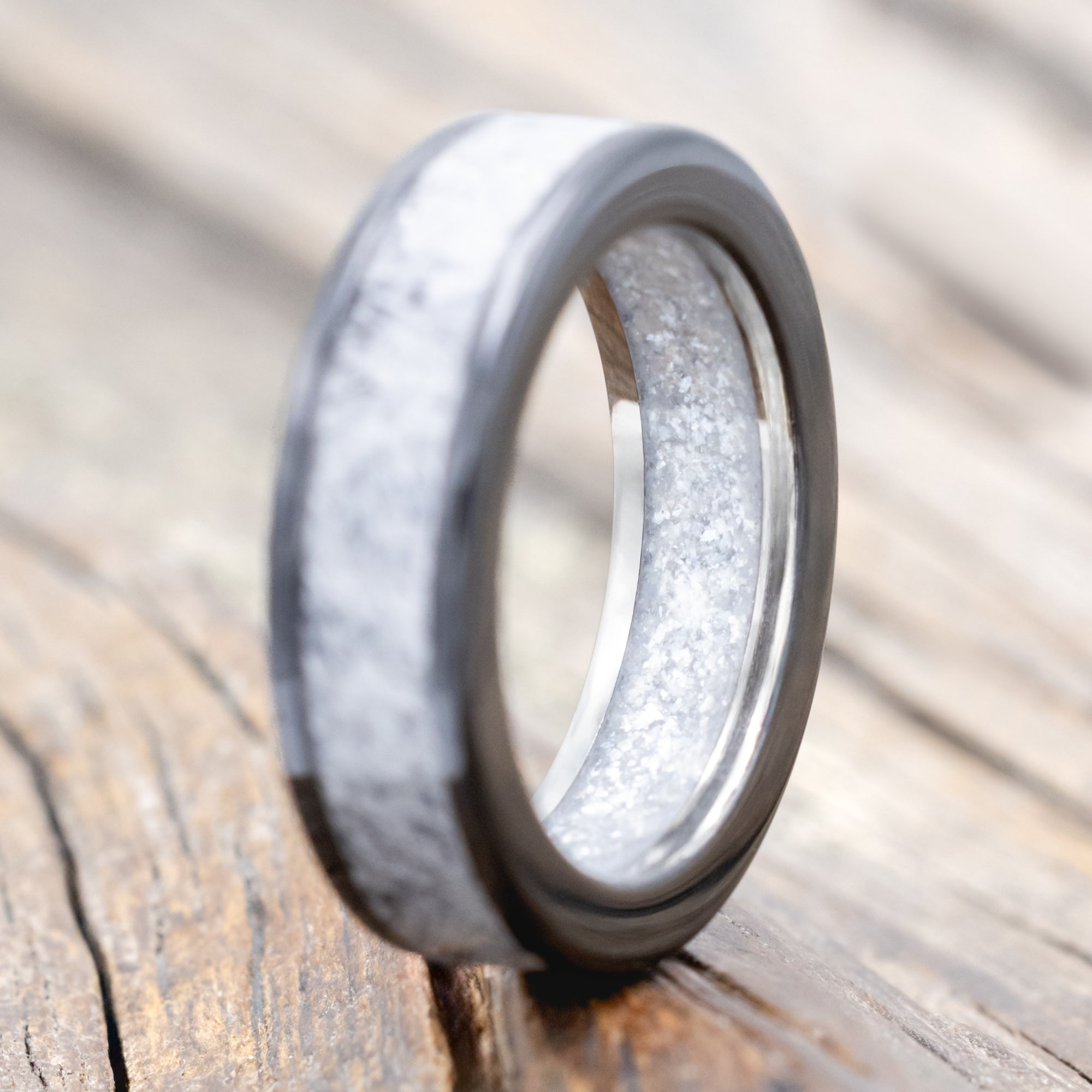 Black zirconium band with wedding dress inlay & diamond dust lining on a wooden surface