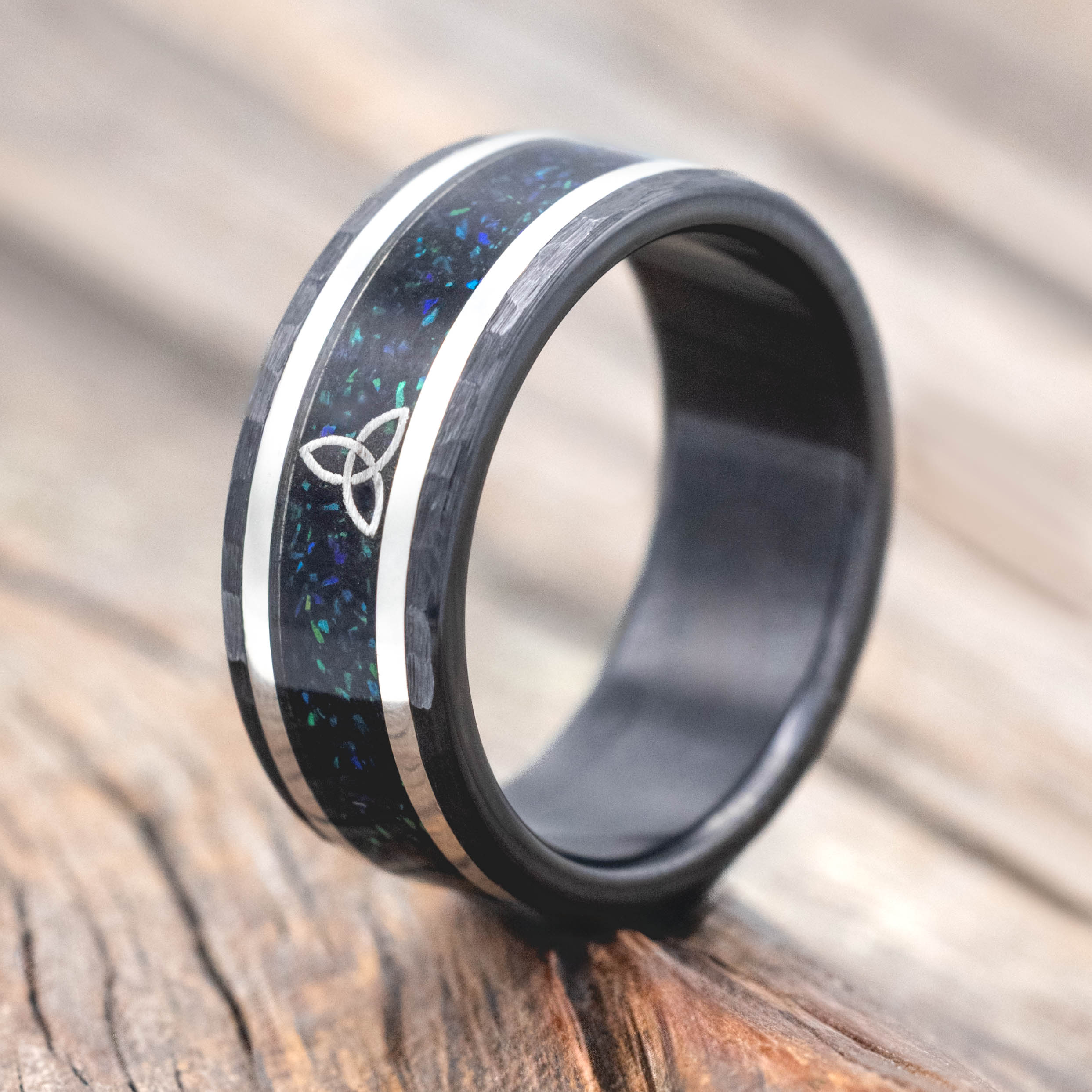 Black ring with a Celtic knot design on a wooden surface